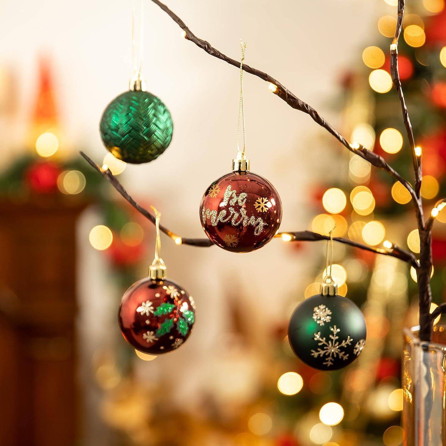 Eine Nahaufnahme eines Weihnachtsbaumzweiges mit roten und grünen Christbaumkugeln, eine davon mit der Aufschrift 