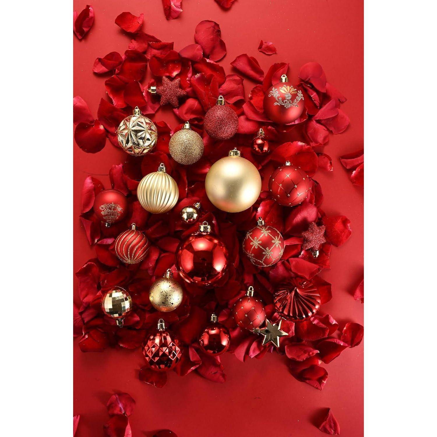 Eine Sammlung verschiedener roter und goldener Weihnachtsornamente und dekorativer Sterne, umgeben von roten Rosenblüten auf einem lebhaft roten Hintergrund.