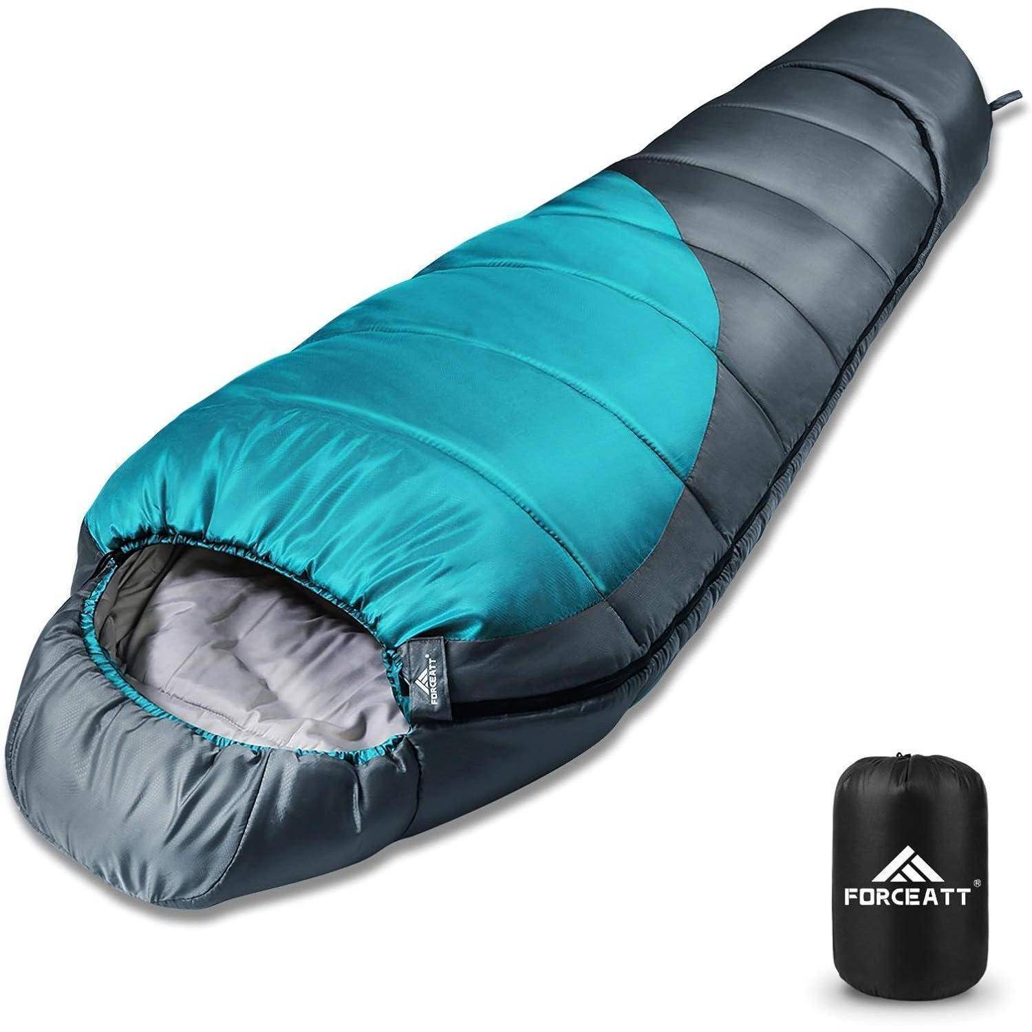 Ein blauer Mumien-Schlafsack, teilweise aufgereißt, neben einem schwarzen Aufbewahrungsbeutel mit dem 'Forceatt' Logo.