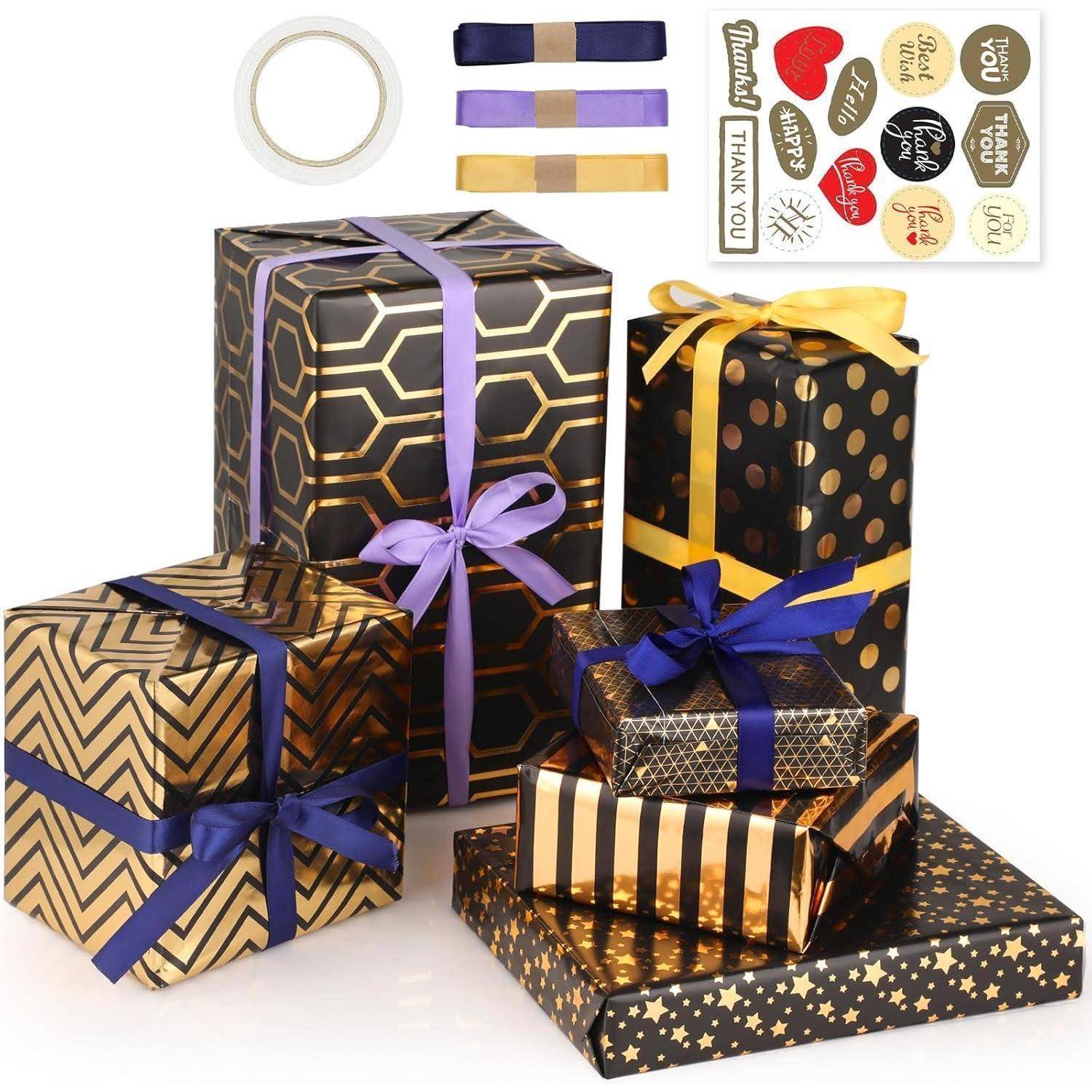 Eine Sammlung von Geschenkboxen, die in verschiedene schwarz-goldene Muster gehüllt sind, mit lila und goldenen Bändern, begleitet von Stickern und Klebeband.