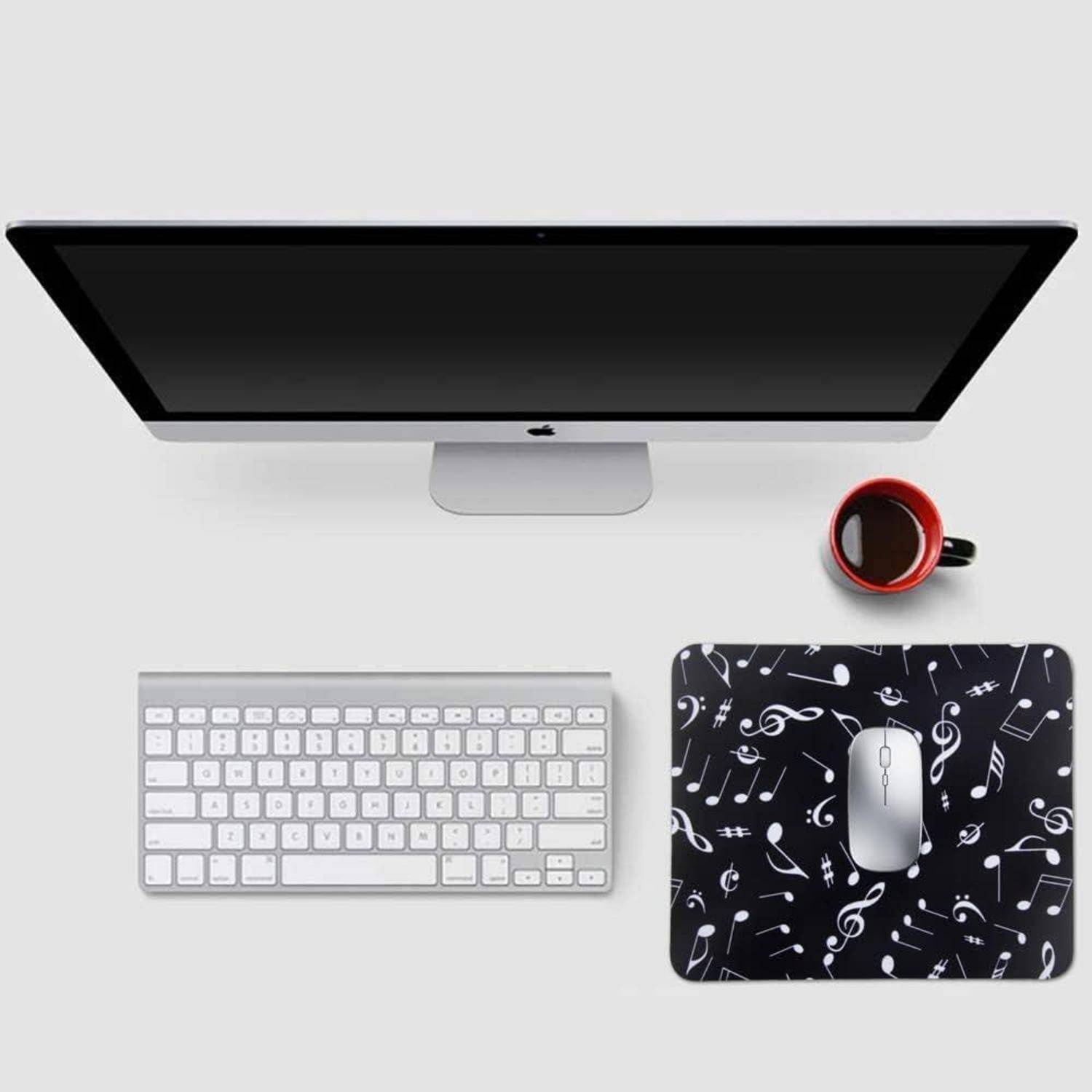 Eine stilvolle Computereinrichtung mit einem Monitor, Tastatur, Kaffeebecher und einer Maus auf einem musikthematischen Mousepad.