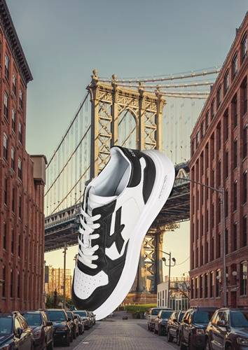 Ein großer Turnschuh, der über eine Stadtstraßenansicht mit einer Hängebrücke im Hintergrund gelegt ist, der urbanen Stil und Architektur hervorhebt.