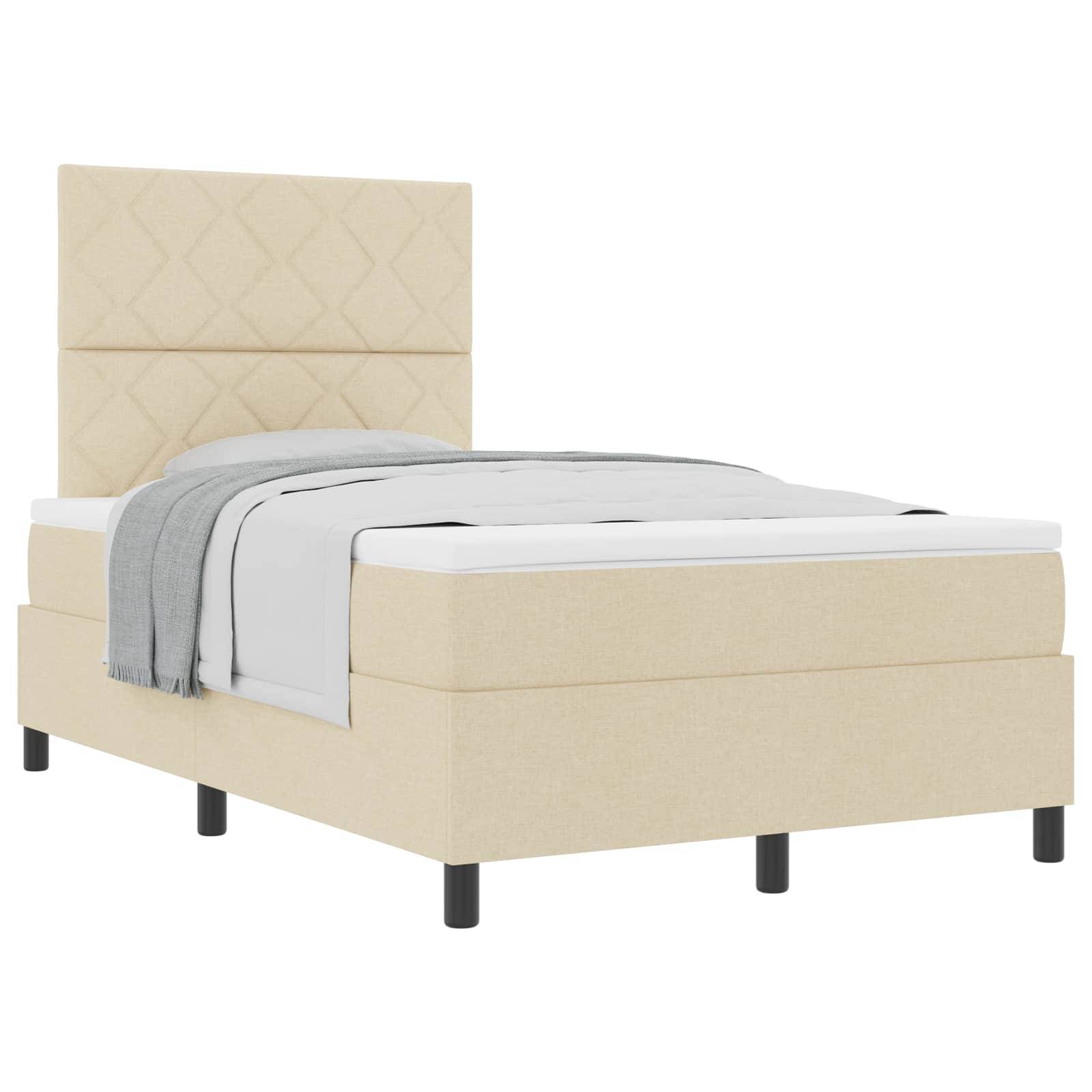 Ein beiges Bett in Zwingröße mit gepolsterter, gesteppter Kopfleiste, weißer Matratze und grauer Decke. Das Bett hat schwarze Beine und ein minimalistisches Design.
