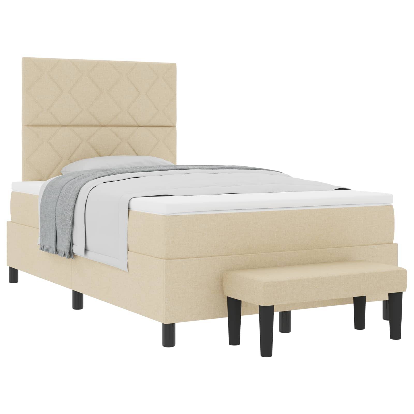 Ein beiges Polsterbett in Einzelgröße mit hohem, gepolstertem Kopfteil, weißen Laken, einer grauen Decke und einer kleinen passenden Bank am Fußende.