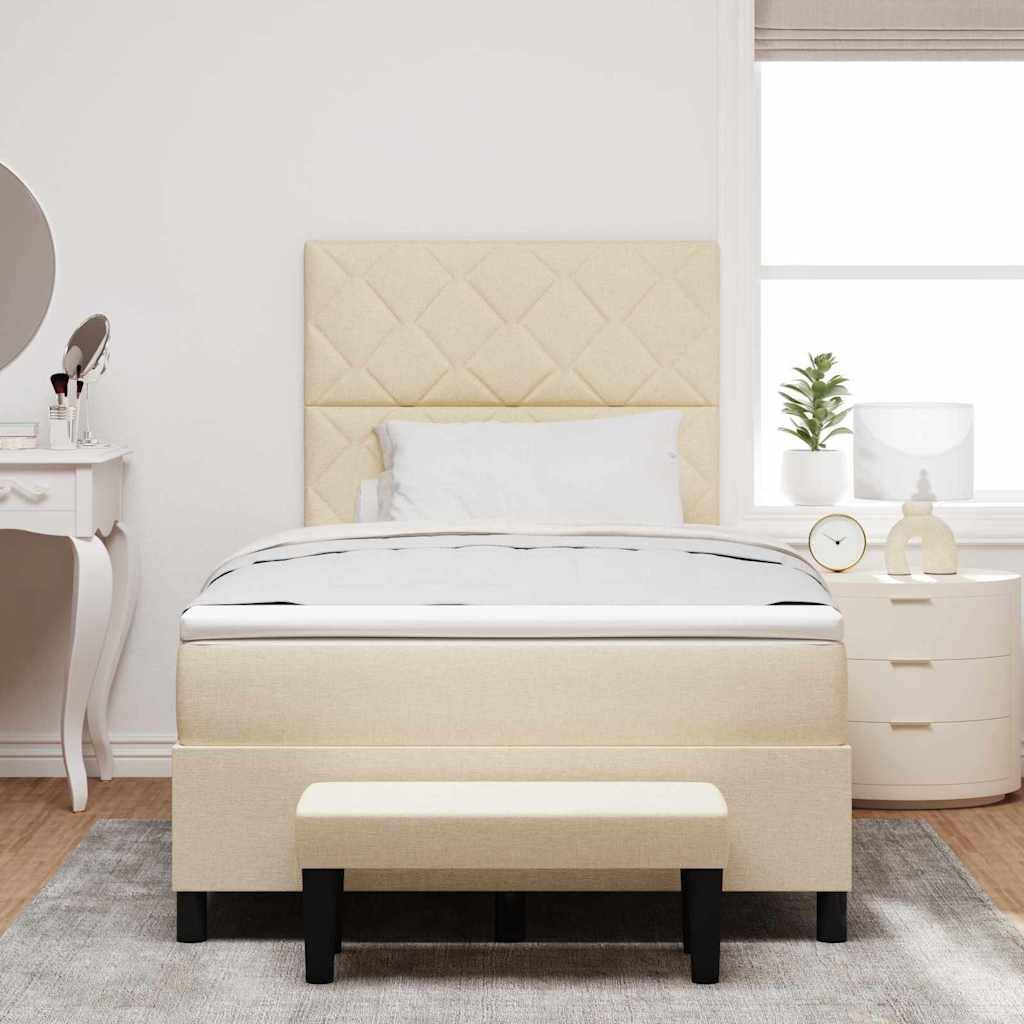 Ein ordentlich gemachtes beiges Bett mit gestepptem Kopfteil ist zentriert zwischen einem Schminktisch auf der linken Seite und einer gerundeten Kommode mit Deko auf der rechten Seite positioniert.