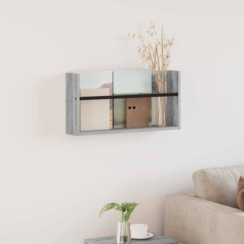 Ein kleines Regal mit dekorativen Vasen und Ordnern hängt an einer hellgefärbten Wand. Ein beiger Sofa und ein Tisch mit einer Pflanze befinden sich in der Nähe.