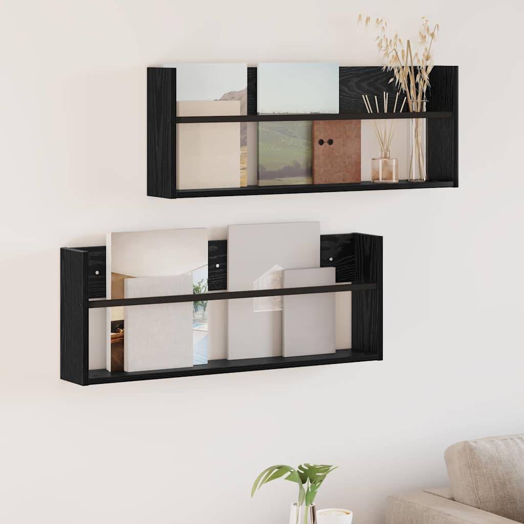 Zwei schwarze Wandregale mit minimalistischem Design, die jeweils Bücher und Dekorationsgegenstände präsentieren. Eine kleine Pflanze befindet sich im unteren Vordergrund.