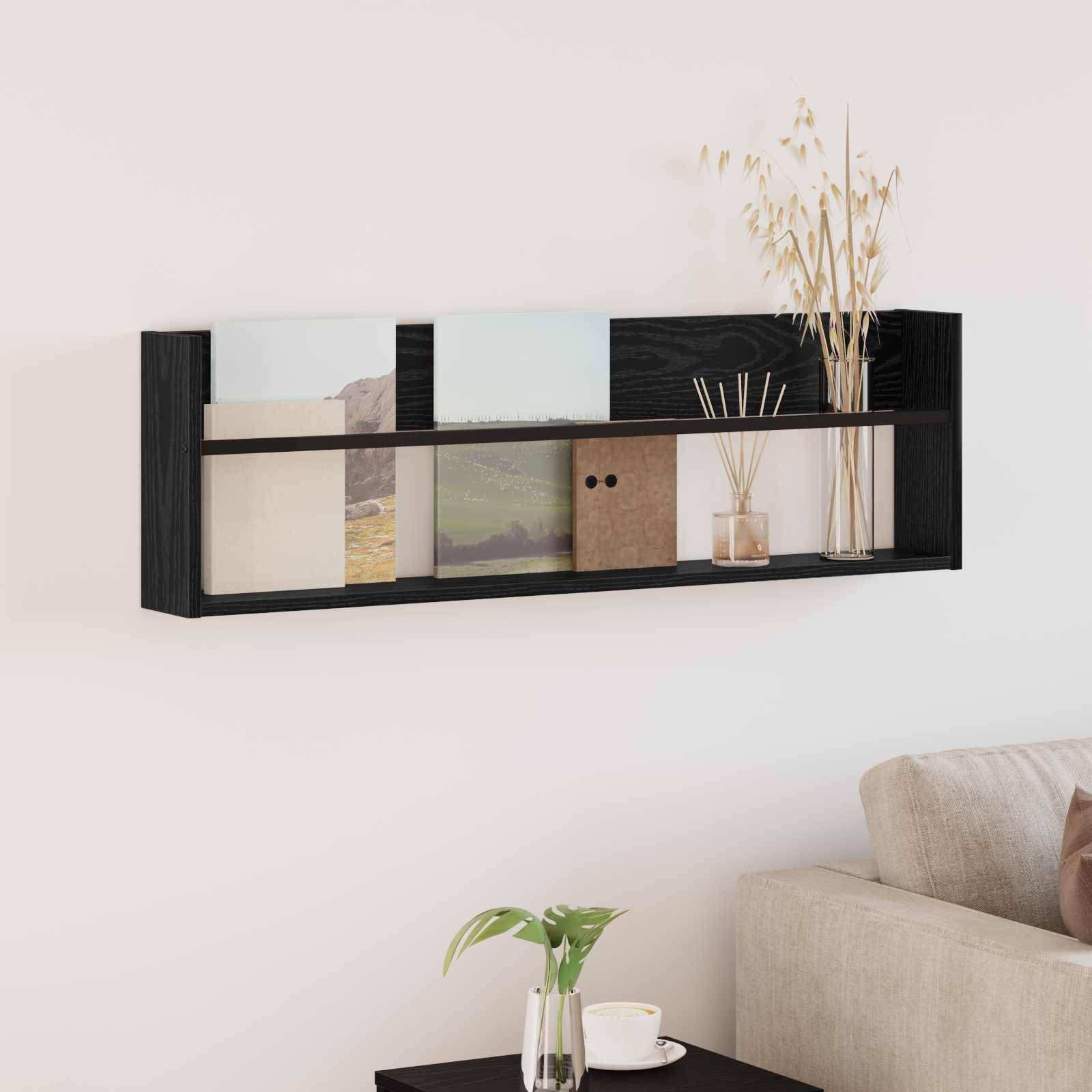 Ein modernes schwarzes Wandregal mit Büchern, einer kleinen Vase und verschiedenen Dekorationselementen, montiert über einem beigen Sofa mit einer Pflanze daneben.