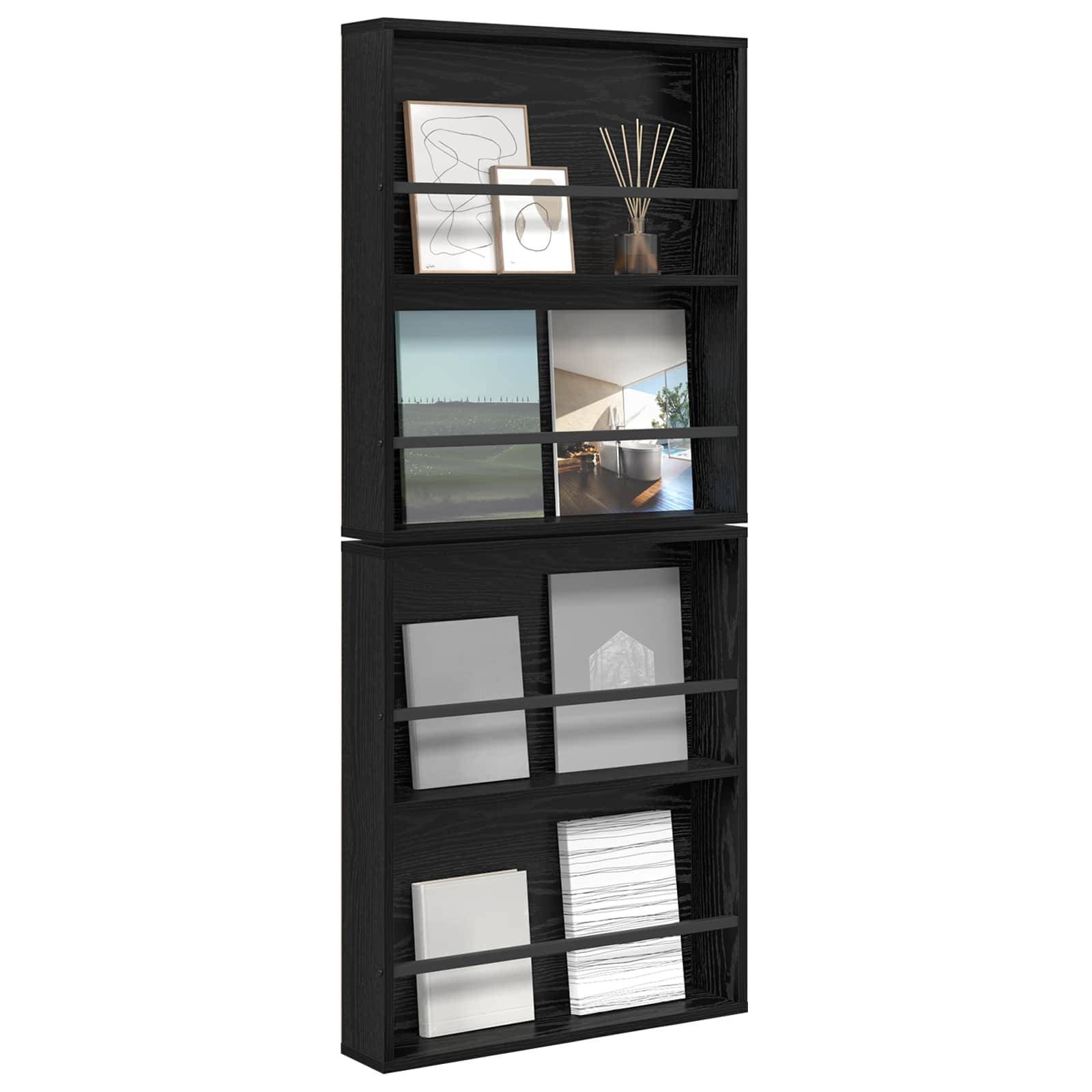 Ein schwarzes, an der Wand befestigtes Bücherregal trägt gerahmte Kunstwerke, einen Diffuser und vertikal angeordnete Bücher. Einige Regale sind minimal bestückt oder leer.