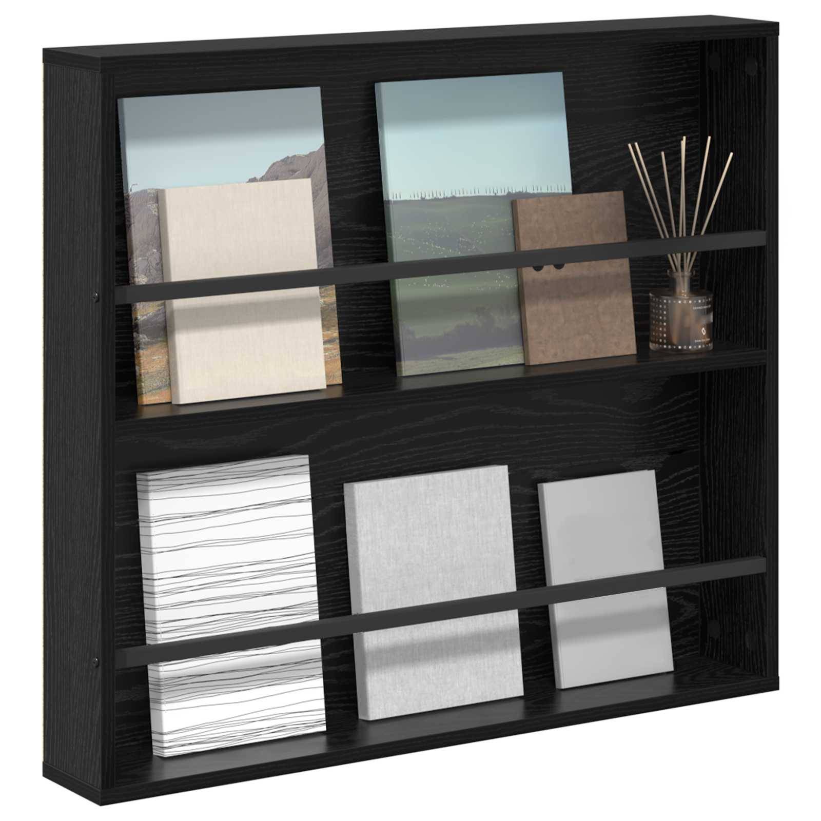 Ein schwarzes, an der Wand befestigtes Regal mit Büchern in verschiedenen Größen und Farben, auf dem rechten oberen Ende ein kleines Glasgefäß mit Reediffusern.