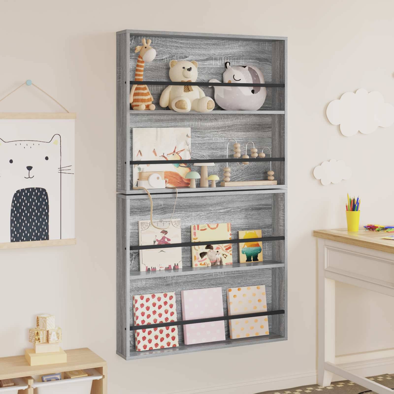 An der Wand montiertes graues Holzregal mit Kinderbüchern und Spielsachen in einem Kinderzimmer, mit einem bärenförmigen Kissen und einem gerahmten Katzendruck.