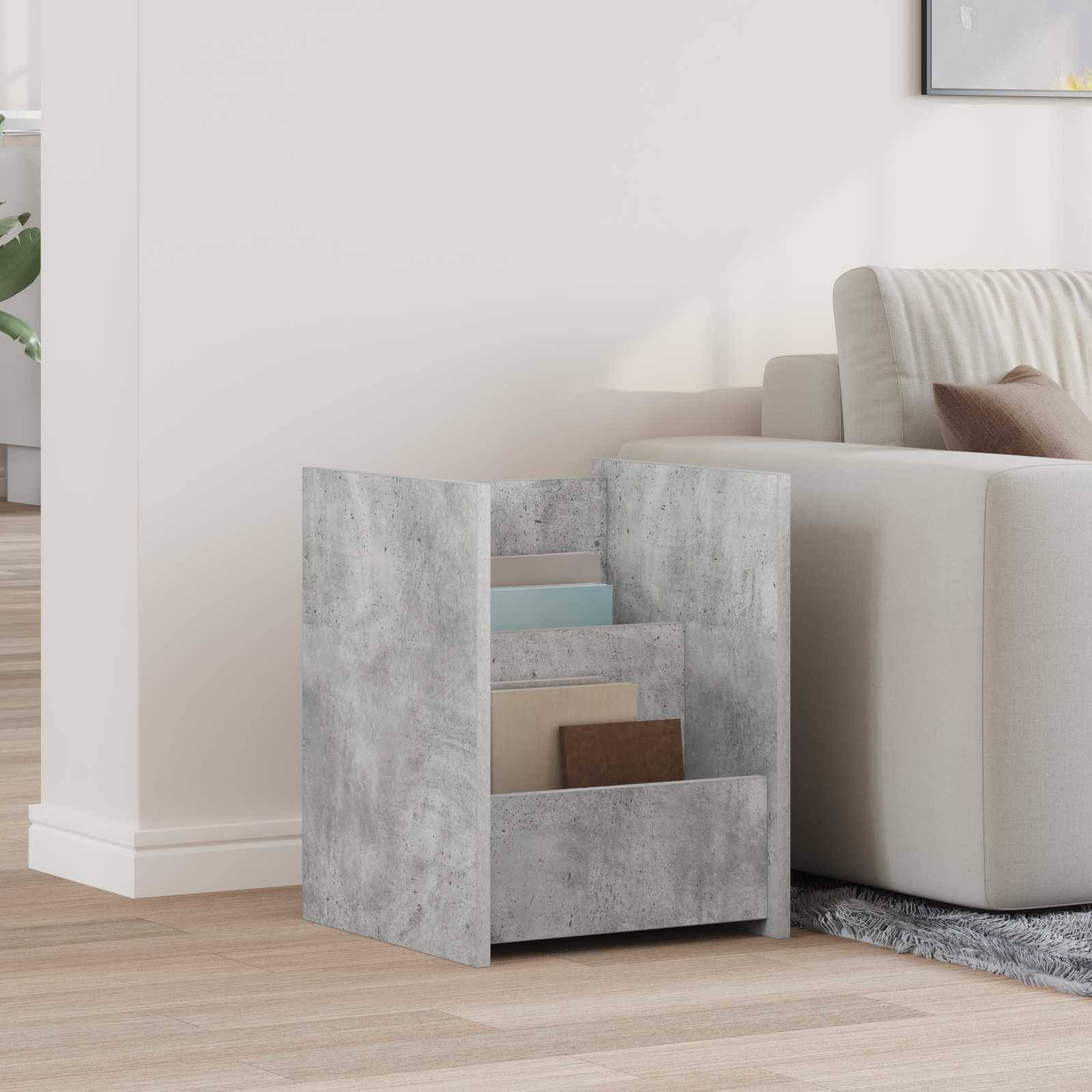 Ein Zeitschriftenhalter mit Betonstruktur und zwei Fächern steht neben einem beigen Sofa in einer minimalistischen Wohnzimmergestaltung.