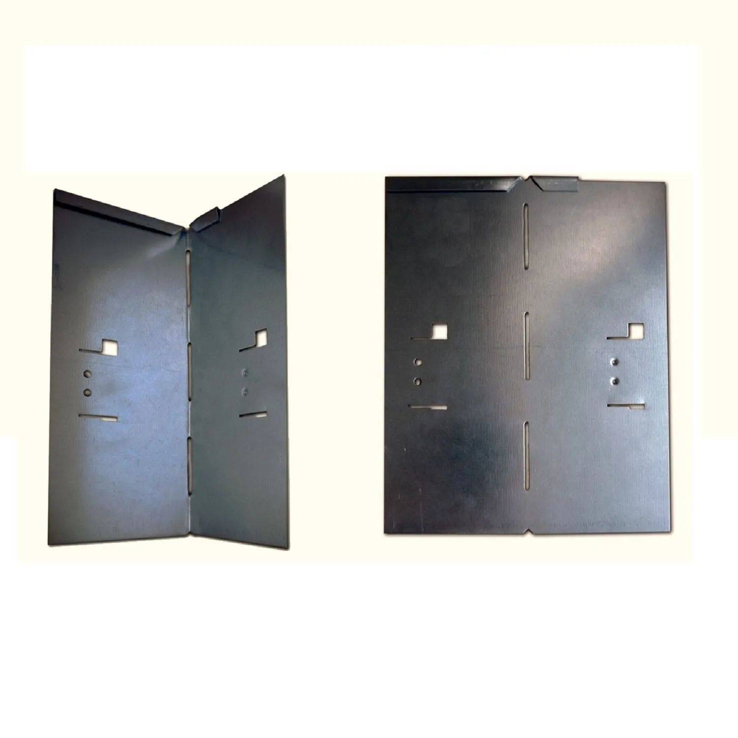 Zwei schwarze Metallpaneele mit Scharnieren und Schlitzen, senkrecht vor einem hellen Hintergrund positioniert, möglicherweise zur Montage oder strukturellen Unterstützung.