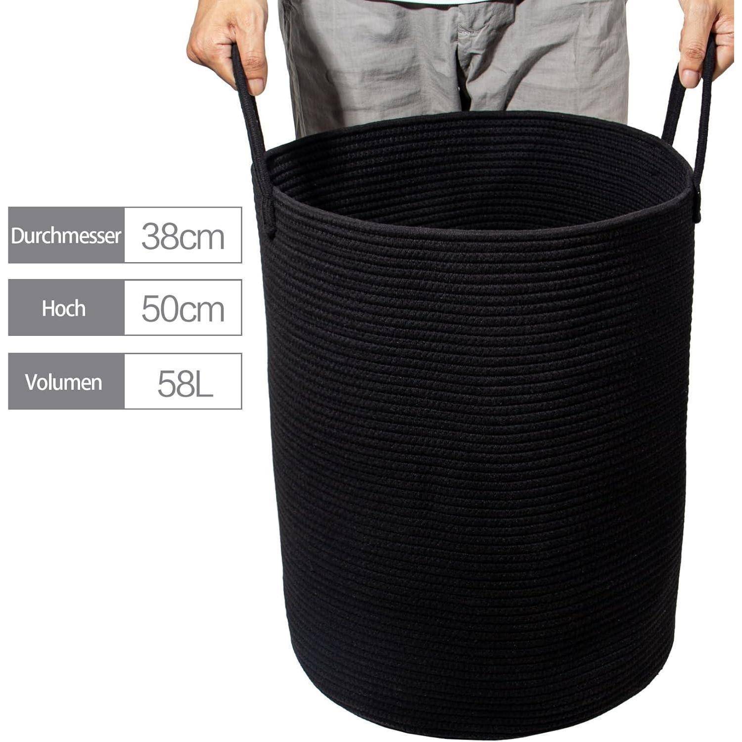Eine Person, die einen schwarzen Korbkorb mit Etiketten hält: ‚Durchmesser 38 cm', ‚Höhe 50 cm', ‚Volumen 58 L'. Der Korb wird aufrecht stehend gezeigt.