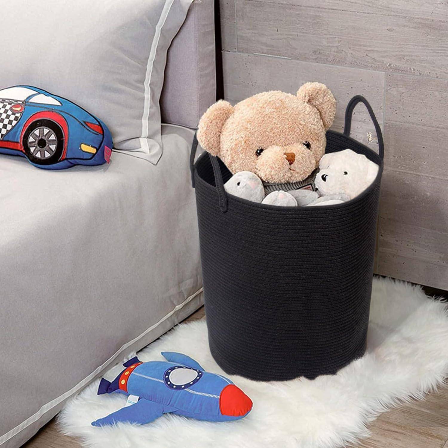 Ein Teddybär und Plüschtiere sitzen in einem schwarzen Korb neben einem Bett mit einem auto-thematischen Kissen. Ein rakettenförmiges Spielzeug liegt auf dem Boden.