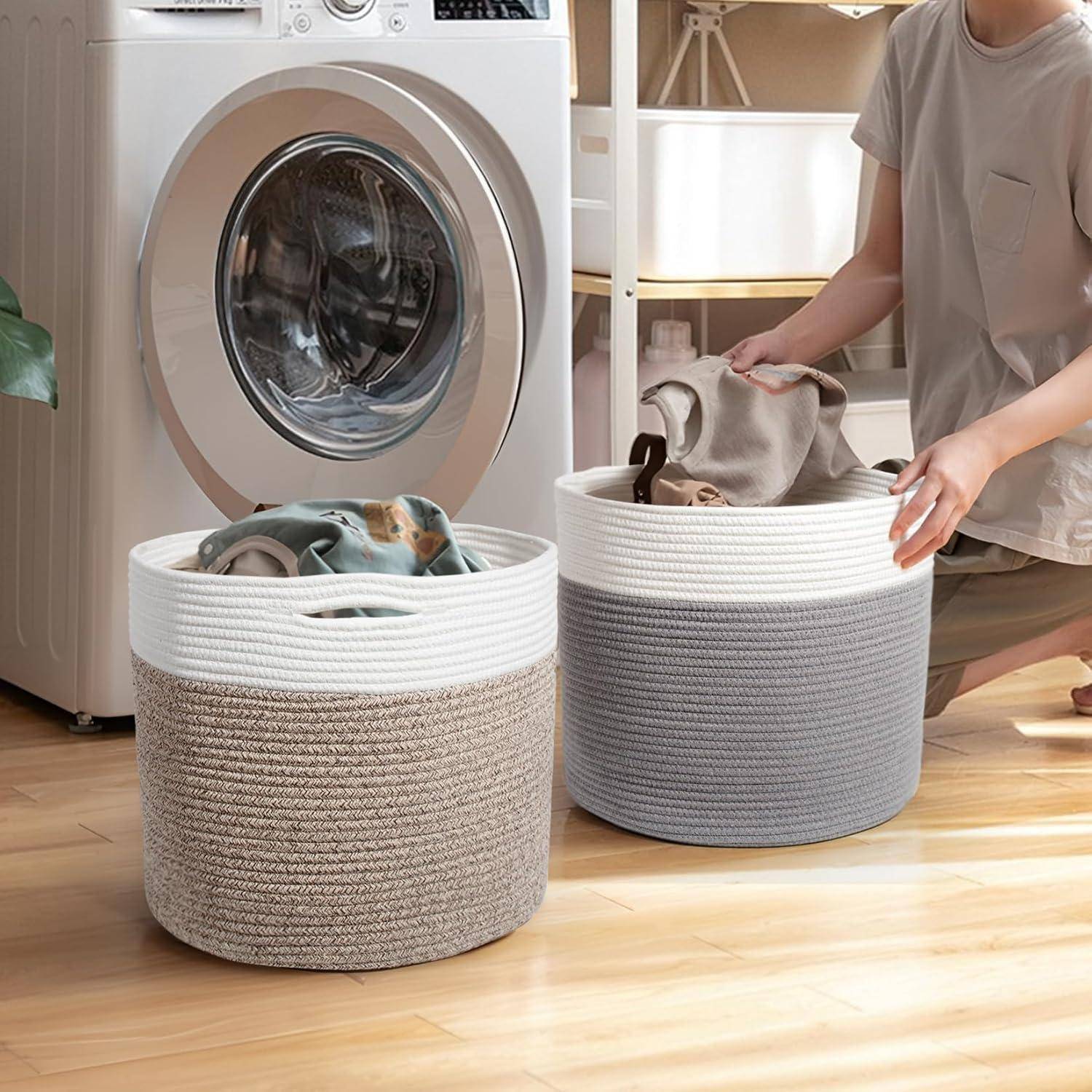 Eine Person legt Kleidungsstücke in einen von zwei Wäschekörben neben einer Frontlader-Waschmaschine auf einem Holzboden.