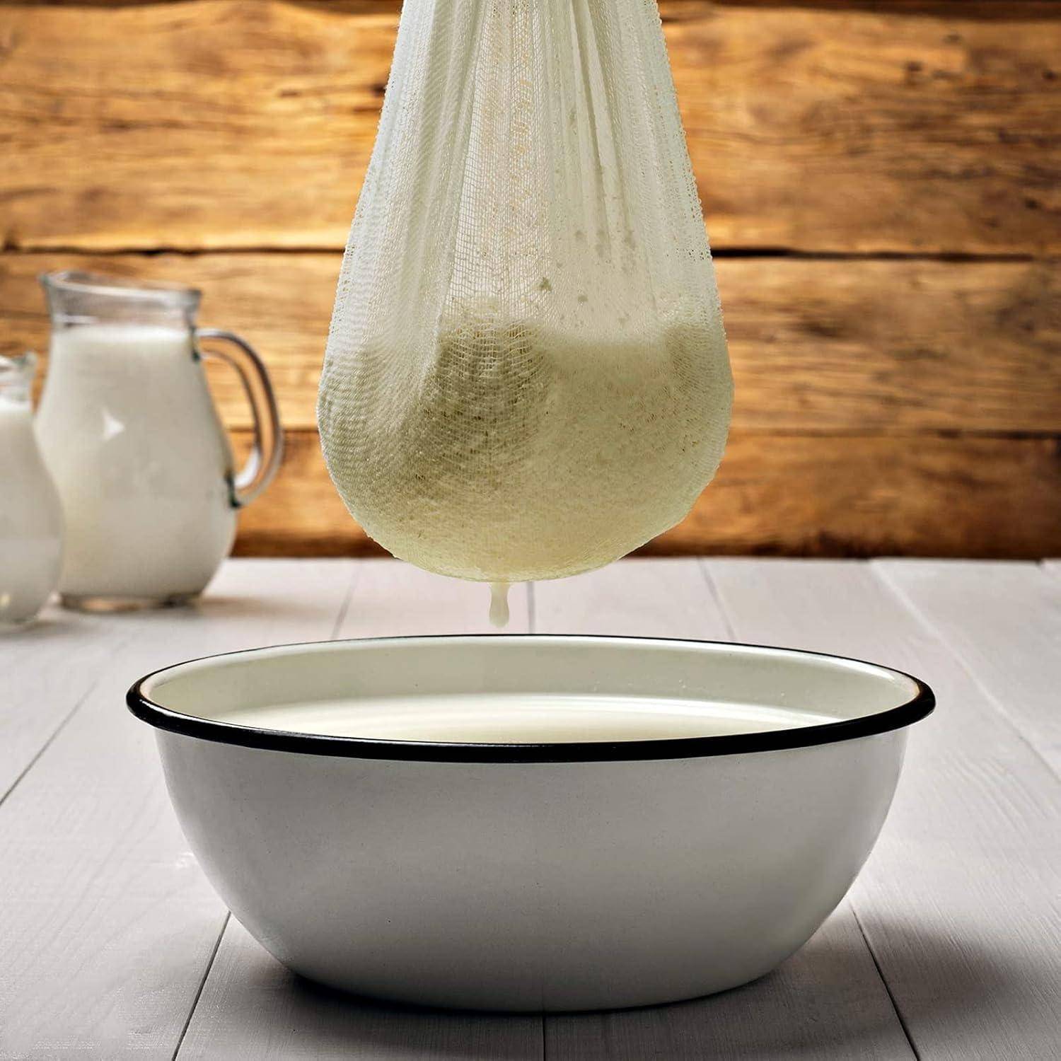 Ein mit Käsekraut gefülltes Passiertuch hängt über einer weißen Schüssel auf einem Holztisch, mit einem Krug Milch im Hintergrund.