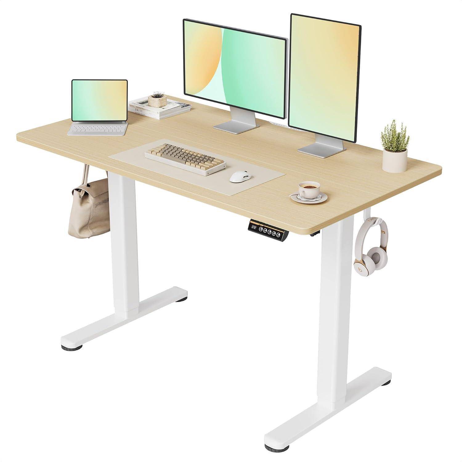 Eine moderne Stehschreibtisch-Einrichtung mit einem Laptop, zwei Monitoren, Tastatur, Maus, Kaffeebecher, Kopfhörern und einer kleinen Topfpflanze.