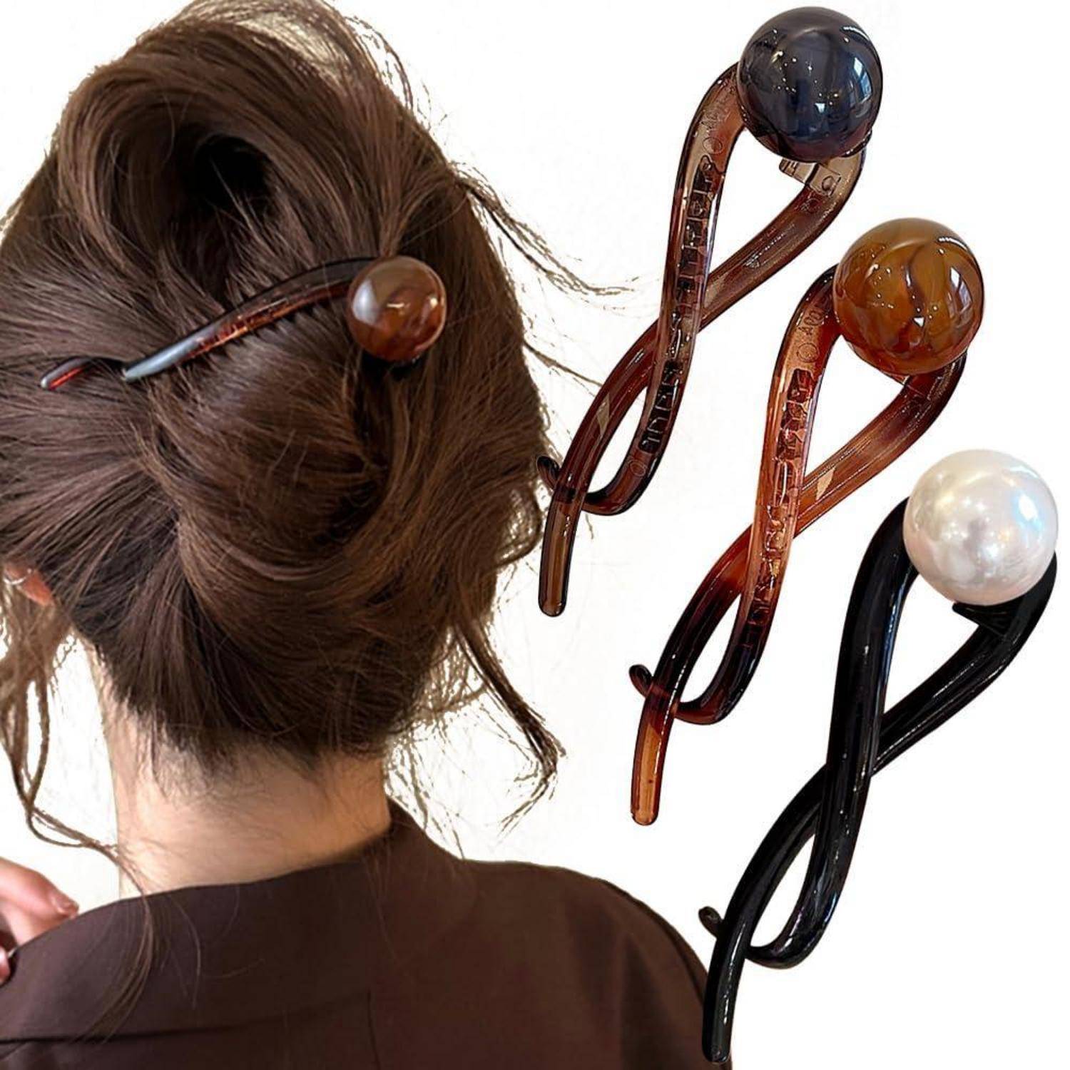 Eine Person mit dunklem Haar, das zu einem Dutt frisiert ist, trägt einen schwarzen Haarstock mit einer großen braunen Kugel. Zwei ähnliche Haarhölzer in Schwarz und Braun mit dekorativen Enden werden daneben präsentiert.