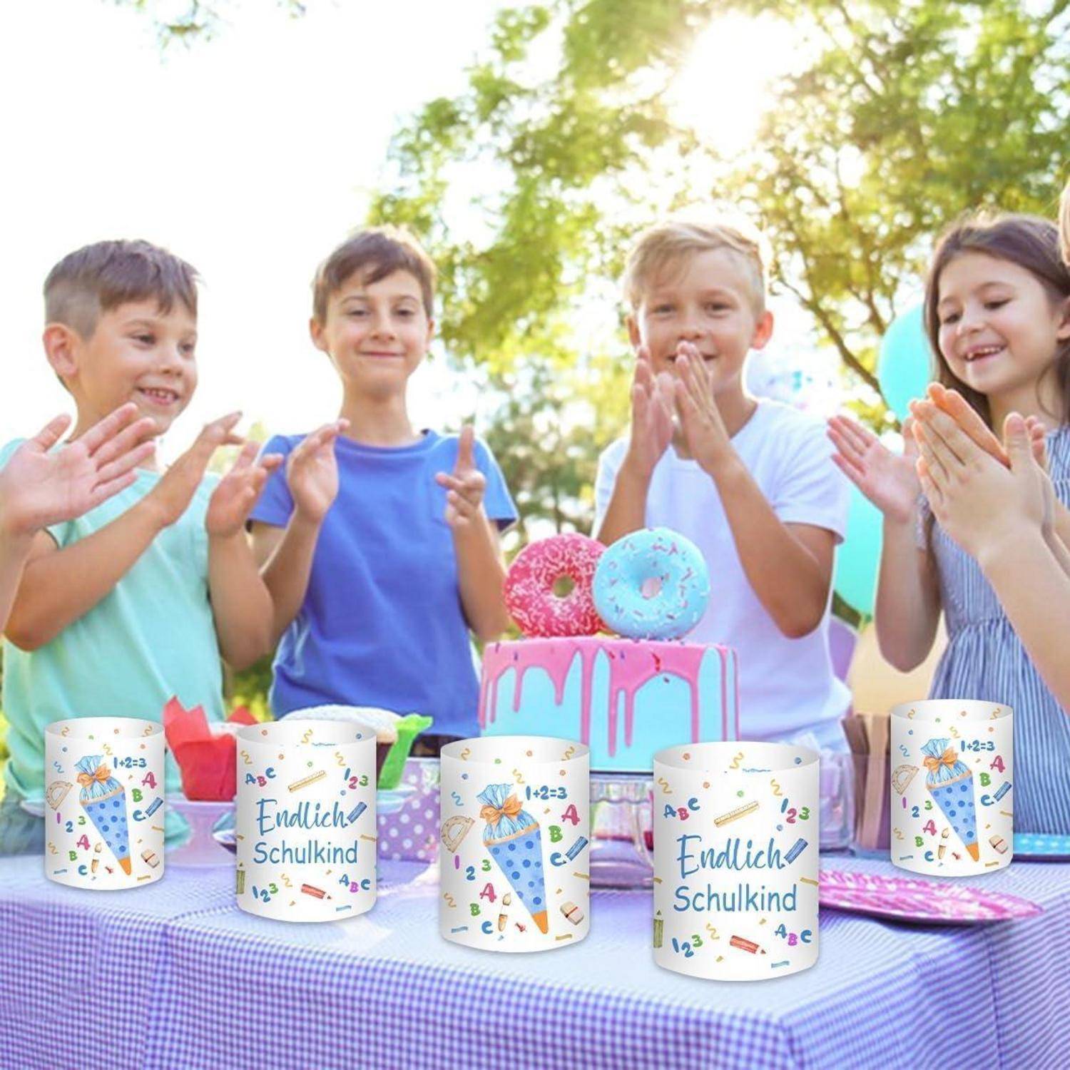 Fünf Kinder lächeln um einen Tisch mit bunten Tassen und Donuts, feiern in einer Außenanlage unter einem sonnigen Himmel.