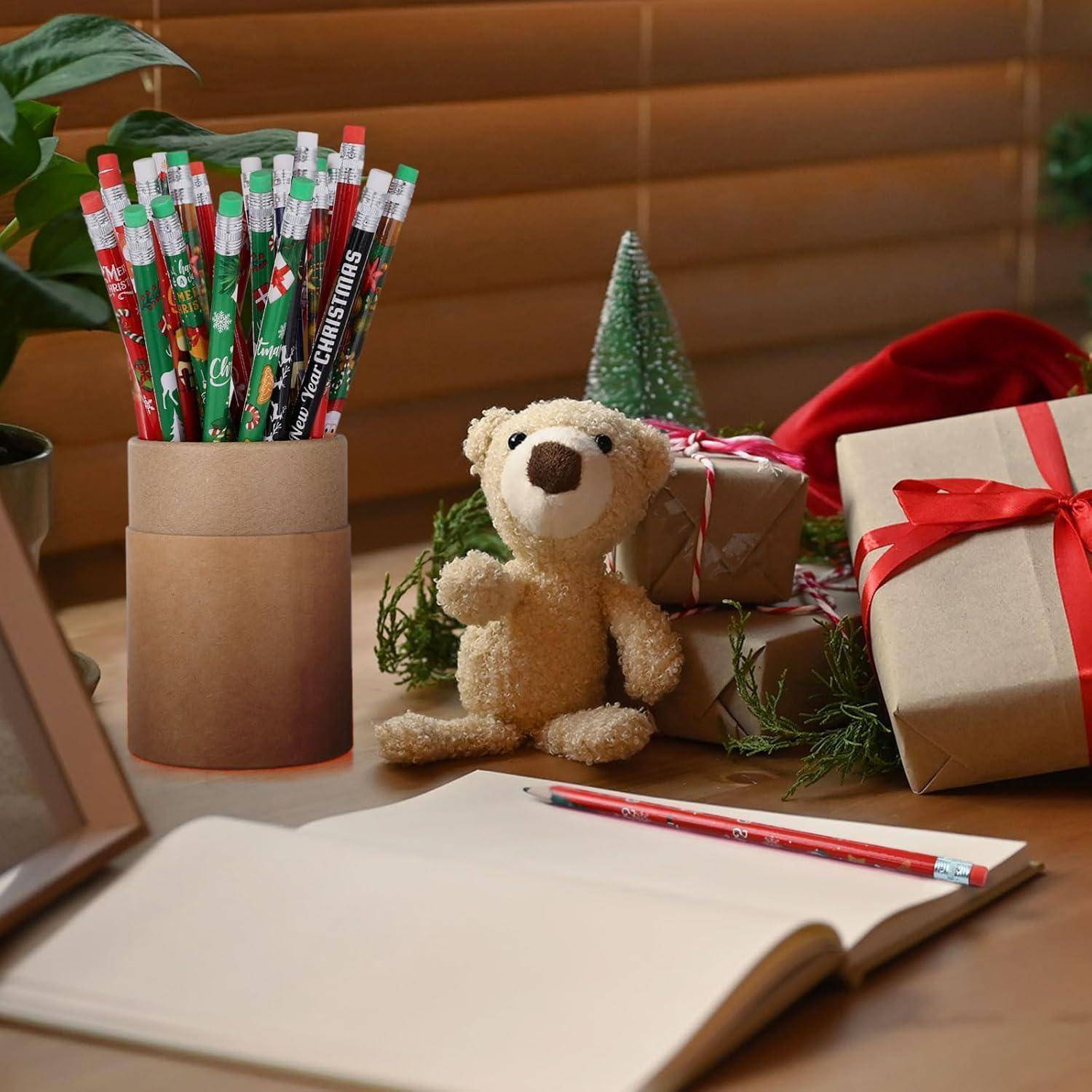 Ein Schreibtisch mit weihnachtlichen Bleistiften, einem Notizbuch, einem Teddybären, Geschenkkartons und einem kleinen Weihnachtsbaum, der eine festliche Atmosphäre schafft.