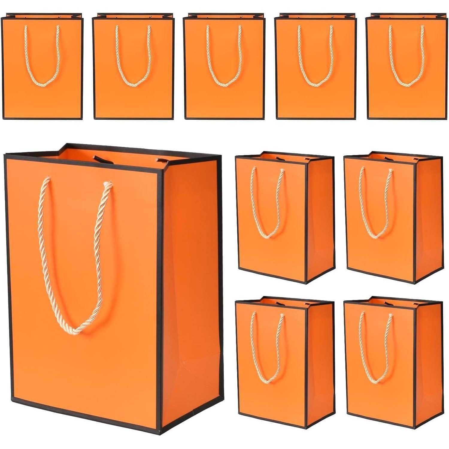 Neun orangefarbene Geschenktaschen mit Kordelhenkeln, eine größere im Vordergrund, die anderen kleiner im Hintergrund, in zwei Reihen angeordnet.