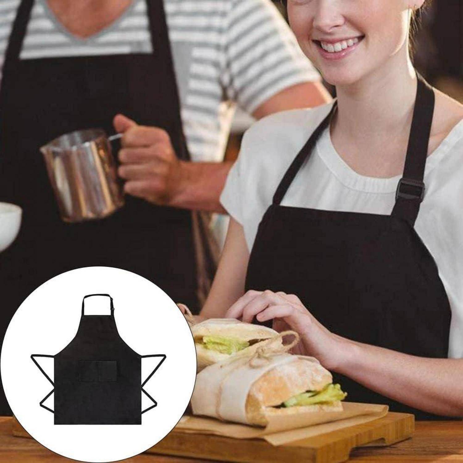 Eine Person mit schwarzer Schürze bereitet Sandwiches auf einem Holzbrett in einer Küchenumgebung vor. Eine andere Person hält einen Milchaufschäumer in der Nähe.