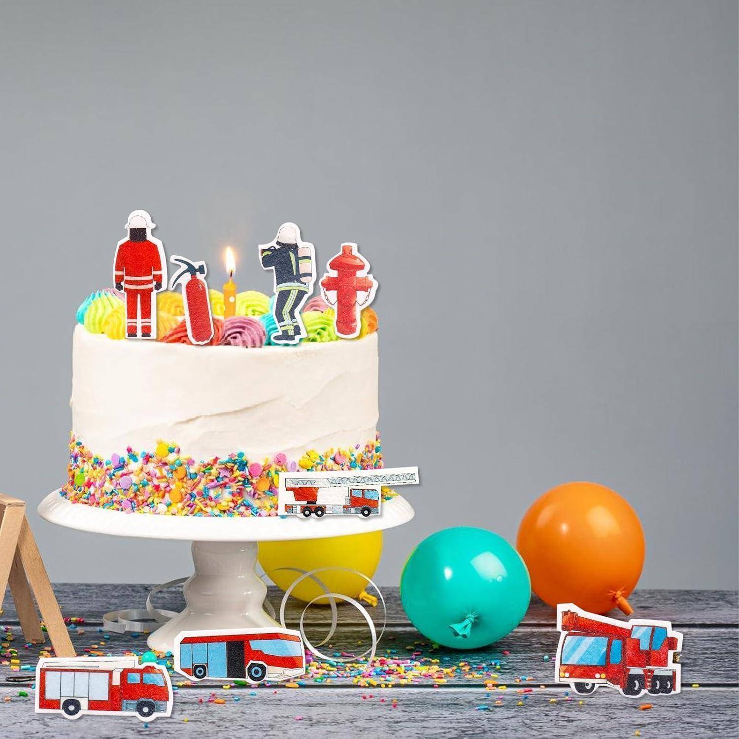 Eine Geburtstagstorte mit bunten Süßigkeiten und Feuerwehr-Themendekoration, einschließlich kleiner Feuerwehrfiguren, umgeben von Luftballons und Spielzeugfeuerwehrautos.