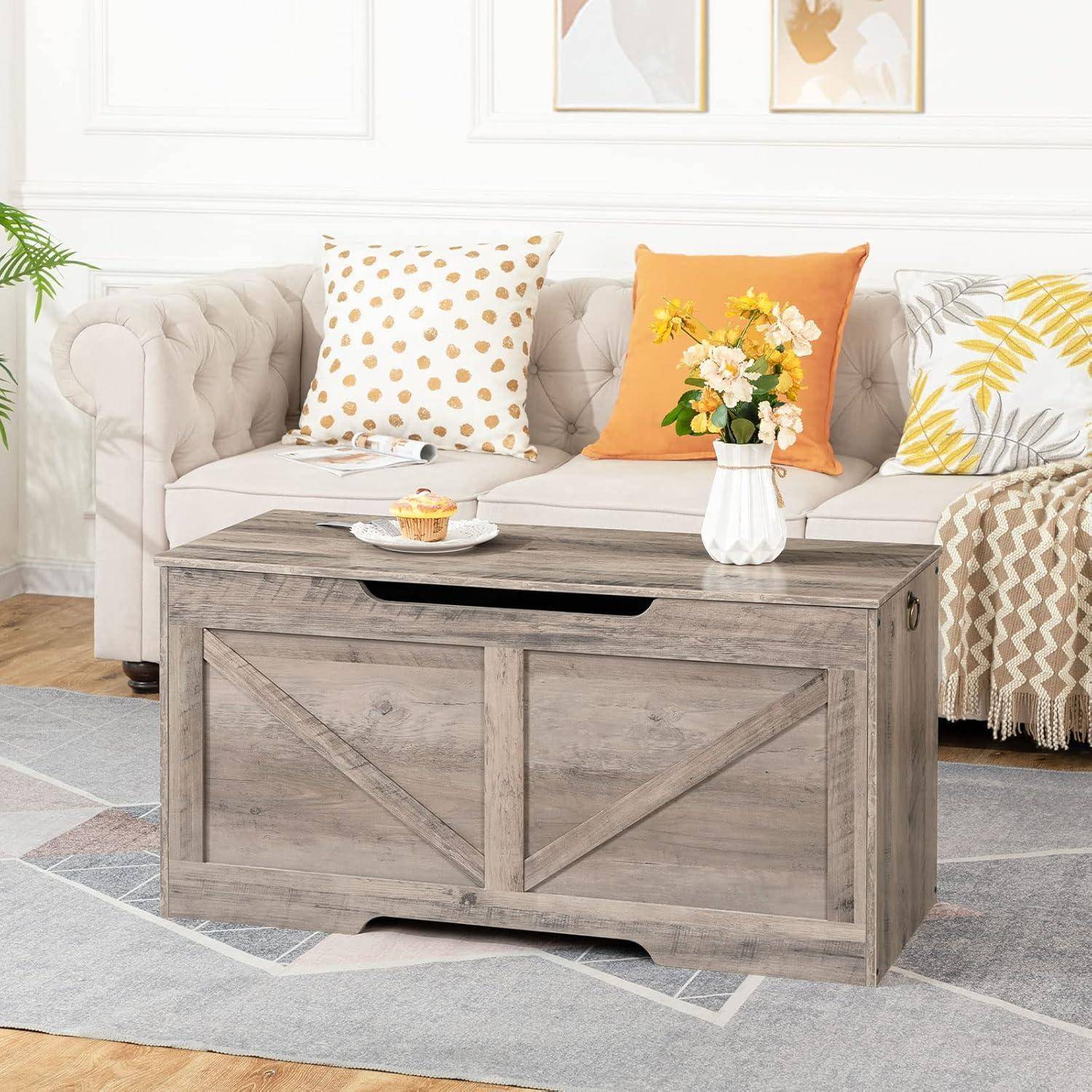 Ein gemütliches Wohnzimmer zeigt ein hellgefärbtes Sofa mit Polka-Dot- und orangefarbenen Kissen. Davor steht eine Holztruhe, die eine kleine Pflanze und eine Kerze beherbergt.