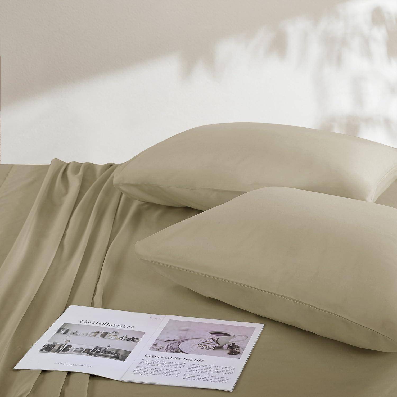 Ein gemütliches Bett mit beigen Laken und zwei Kissen. Eine aufgeschlagene Zeitschrift liegt auf dem Bett und zeigt Schwarz-Weiß-Bilder und Text.