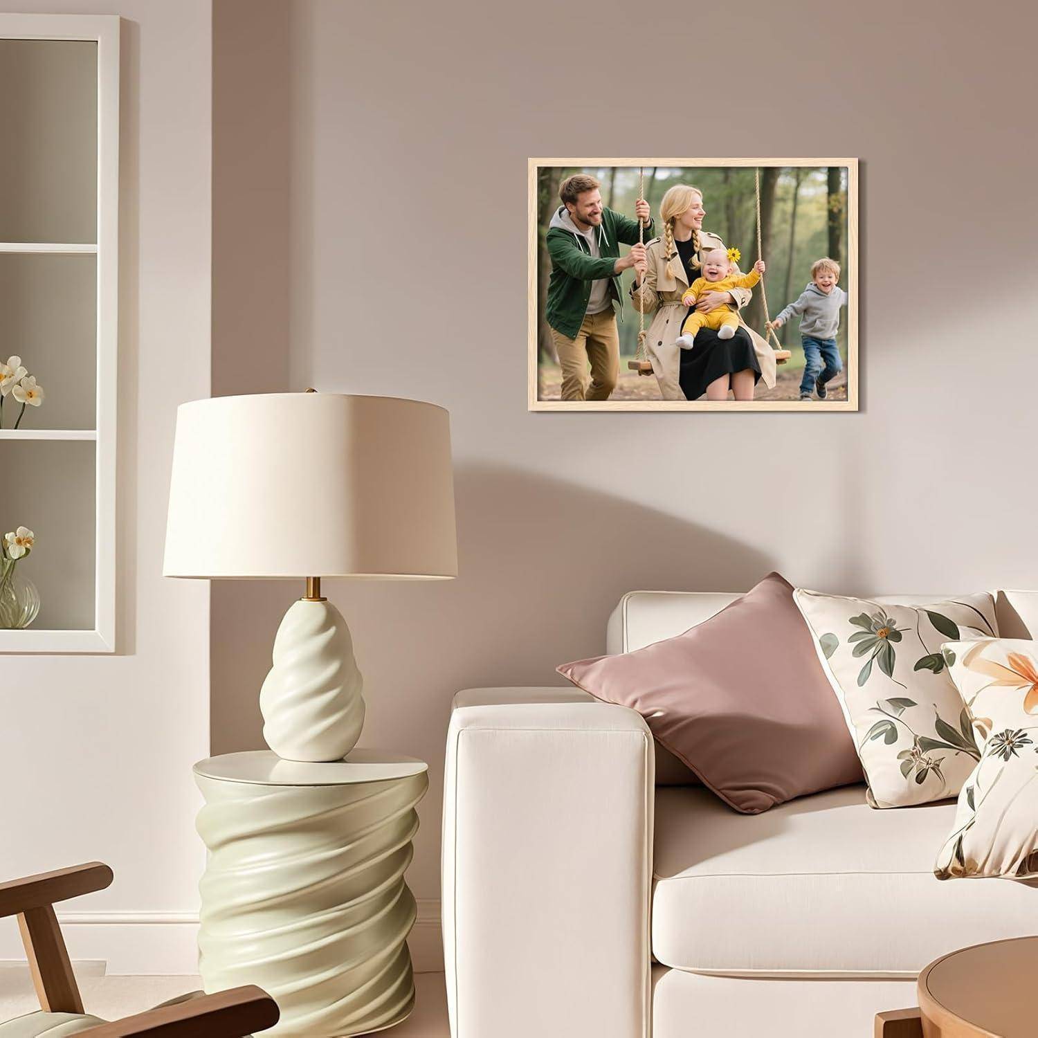 Ein Wohnzimmer mit einem beigen Sofa, rosa und blumigen Kissen, einer modernen Lampe und einem Foto an der Wand, das eine Familie zeigt, die in einem Park spielt.