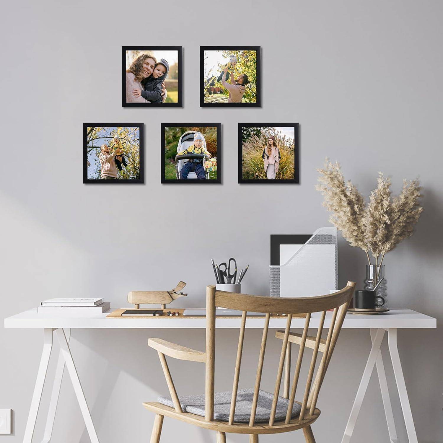 Ein modernes Home Office mit einem Schreibtisch, einem Stuhl und an der Wand montierten Bilderrahmen, die Familienmomente zeigen. Eine Vase mit getrockneten Blumen steht auf dem Schreibtisch.
