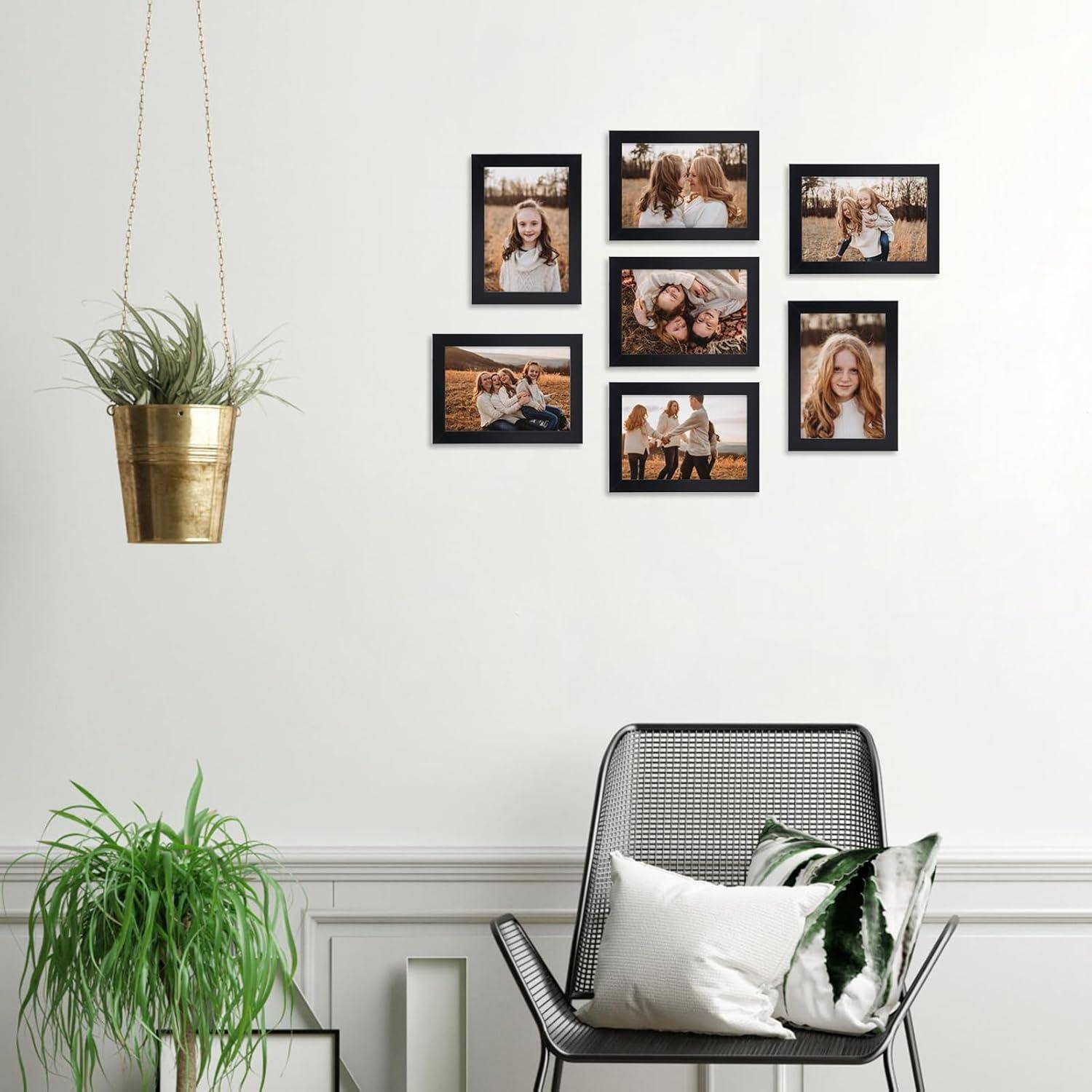 Eine Wand mit einer Collage aus sieben gerahmten Familienfotos über einer Topfpflanze und einem modernen Stuhl mit einem gemusterten Kissen in einem Wohnzimmer.