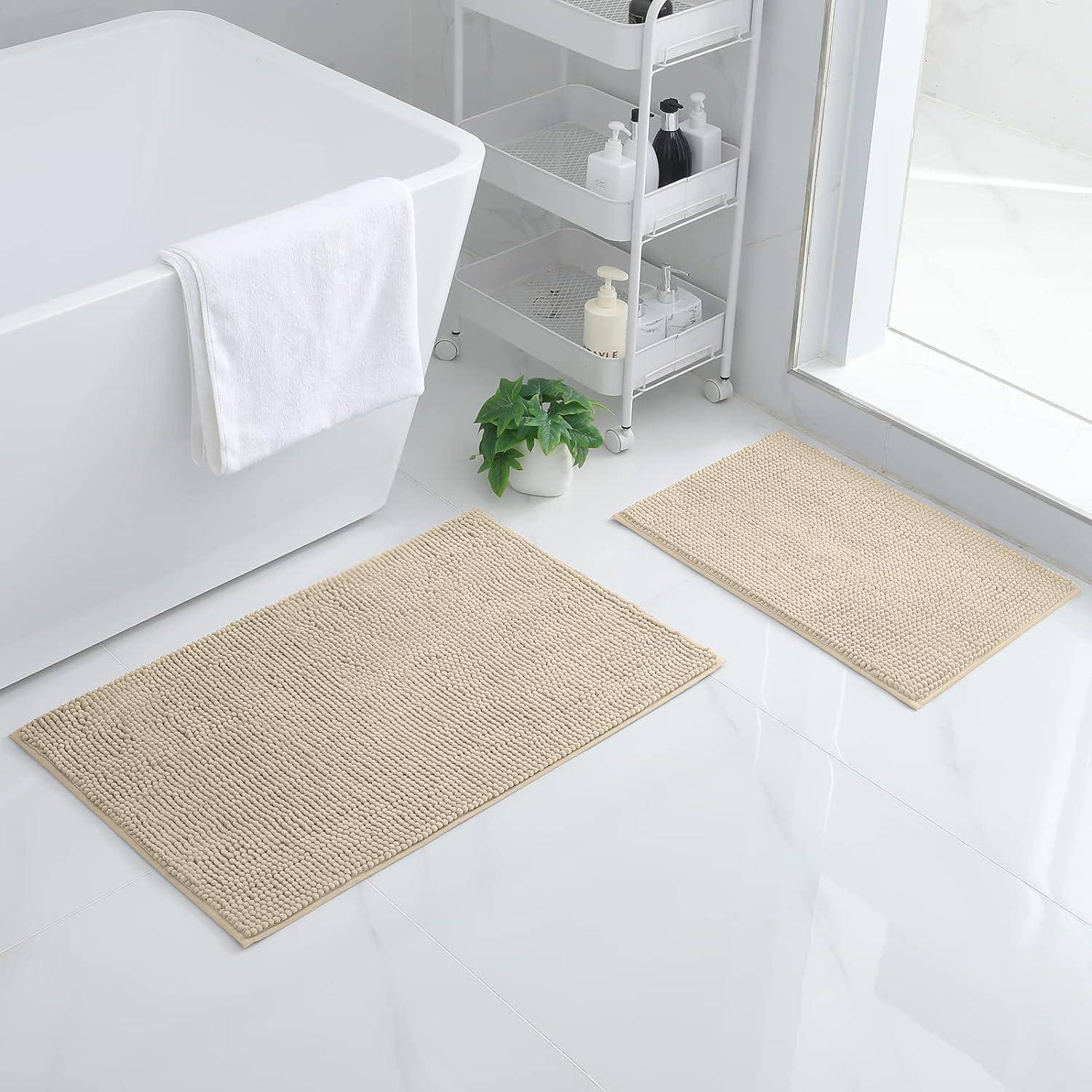 Ein modernes Badezimmer zeigt eine weiße Badewanne mit einem über den Rand gelegten Handtuch, zwei beigen Matten auf dem Boden und einen Wagen mit Toilettenartikeln.
