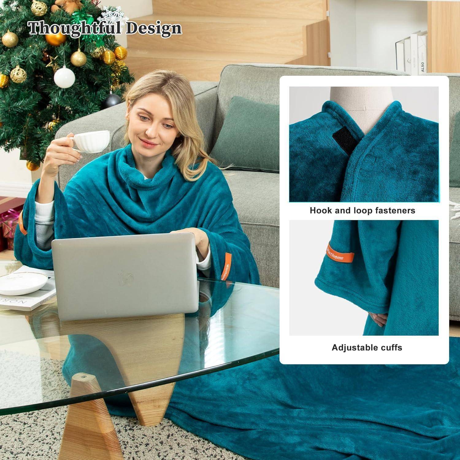 Eine Person sitzt auf einem Sofa, arbeitet an einem Laptop und trinkt aus einer Tasse, eingehüllt in eine blaue Kuscheldecke; im Hintergrund steht ein Weihnachtsbaum.