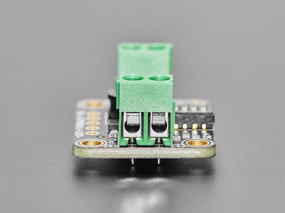 Eine Nahaufnahme eines kleinen elektronischen Sensormoduls mit einem grünen Anschlussblock zum Anschließen von Kabeln auf einem grauen Hintergrund.