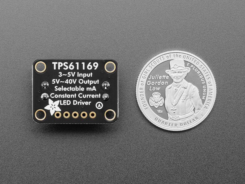 Adafruit-Modul TPS61169 mit Eingabe-/Ausgabespezifikationen, gedruckt auf einer kleinen schwarzen Leiterplatte neben einer US-Vierteldollar-Münze zur Größenvergleichsdarstellung.