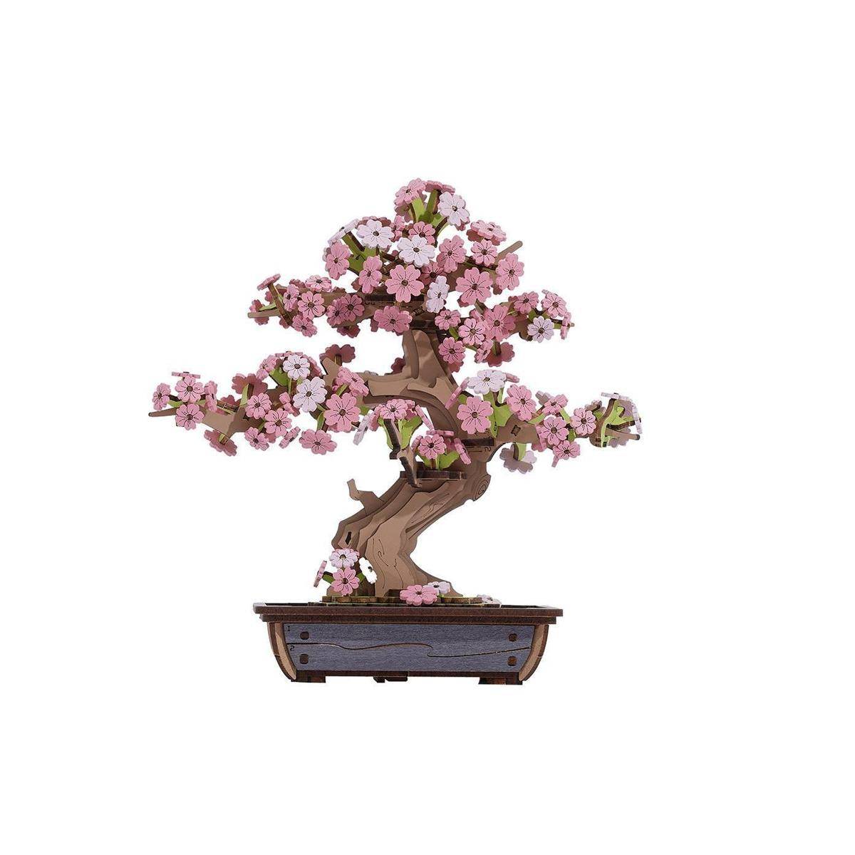 Ein Miniatur-Bonsai-Baum-Modell mit rosa und weißen Blüten, platziert in einem kleinen, rechteckigen Topf auf weißem Hintergrund.