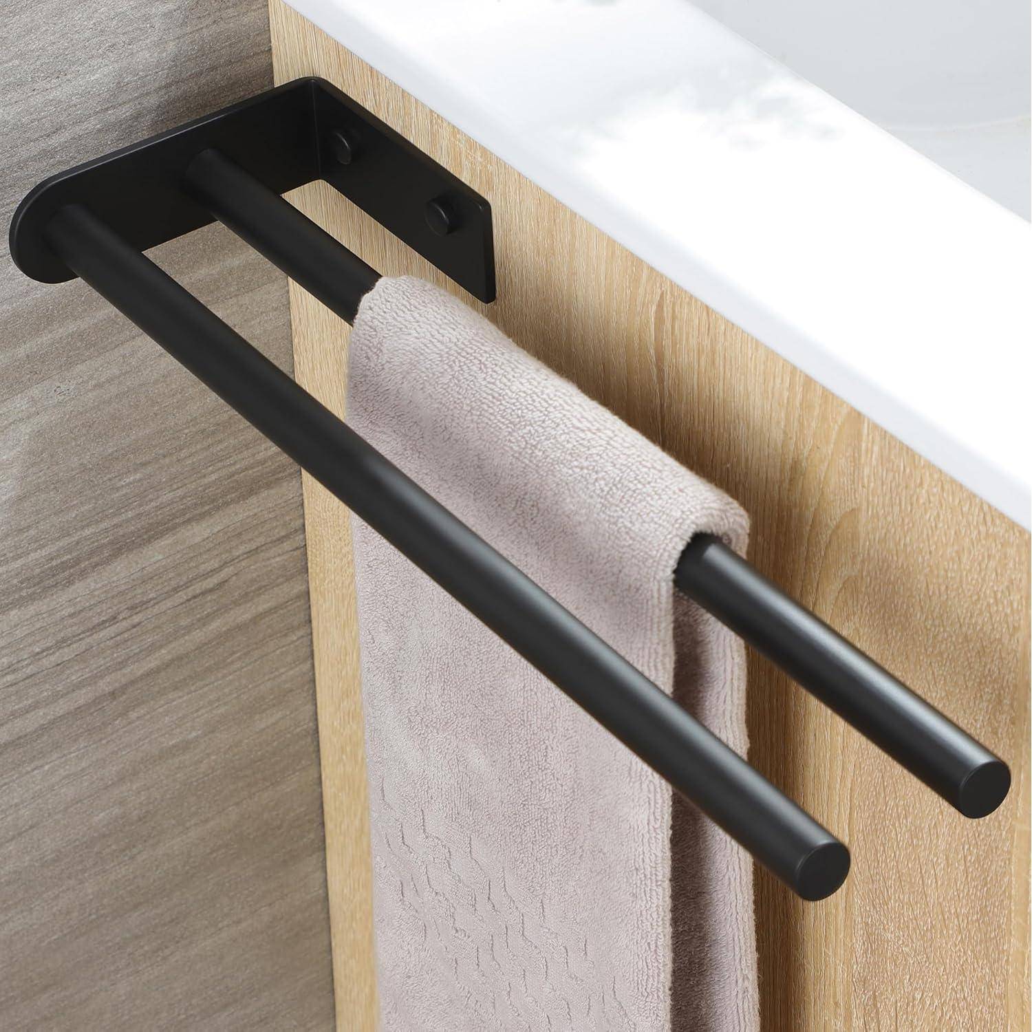 Eine schwarze doppelte Handtuchstange, die an einer Holzplatte befestigt ist, hält ein beiges Handtuch. Die Platte grenzt an eine weiße Oberfläche, möglicherweise eine Arbeitsplatte.