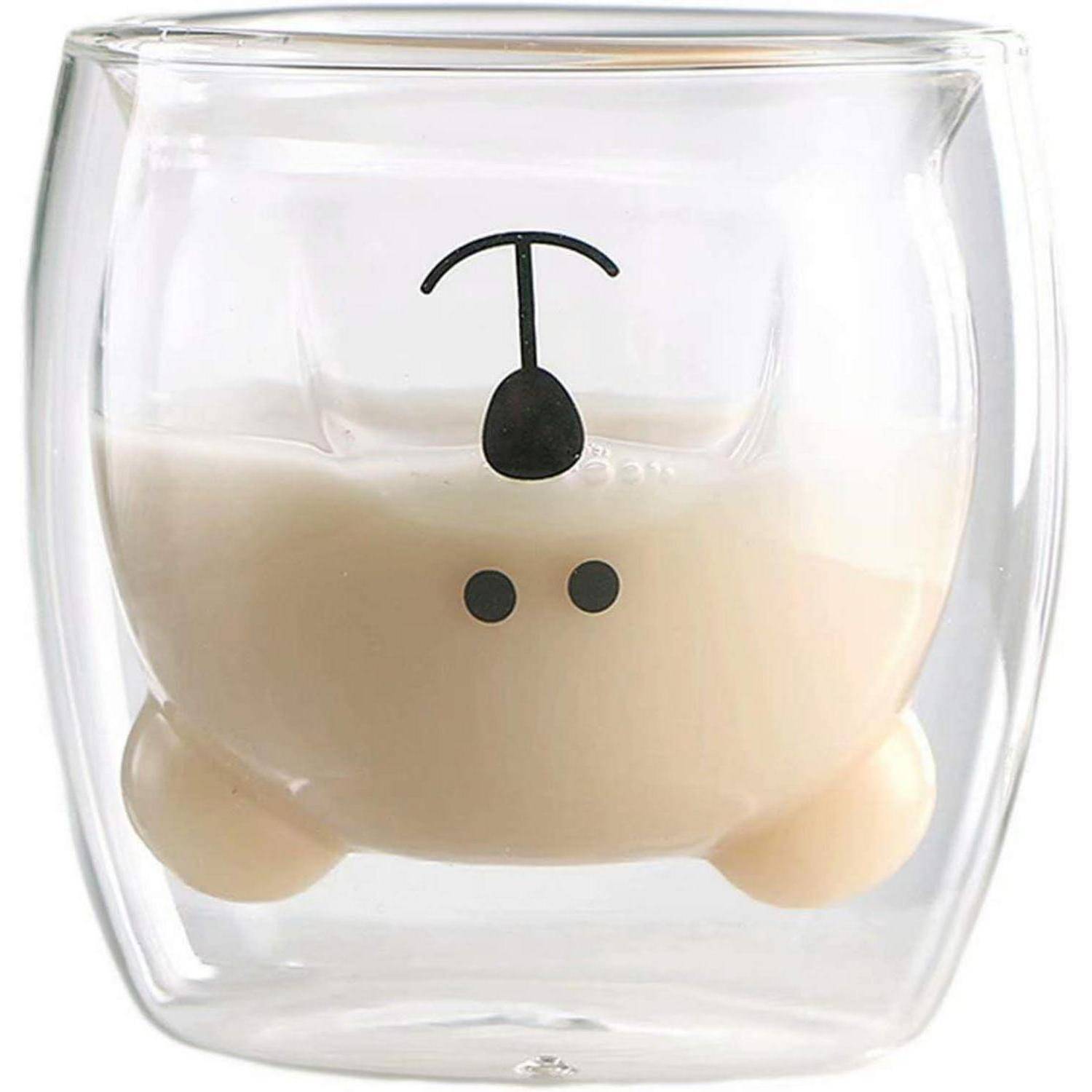 Ein transparentes, doppelwandiges Glas mit Milch im Inneren, das mit einem niedlichen auf dem Kopf stehenden Tiergezicht gestaltet ist, mit Augen, Nase und Ohren.