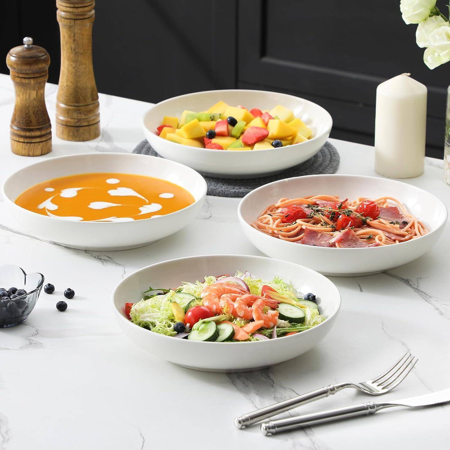 Ein Tisch mit einer Schüssel cremiger Suppe, Salat mit Gurken und Lachs, Pasta mit Tomaten und Prosciutto und eine Schüssel mit gemischten Früchten.