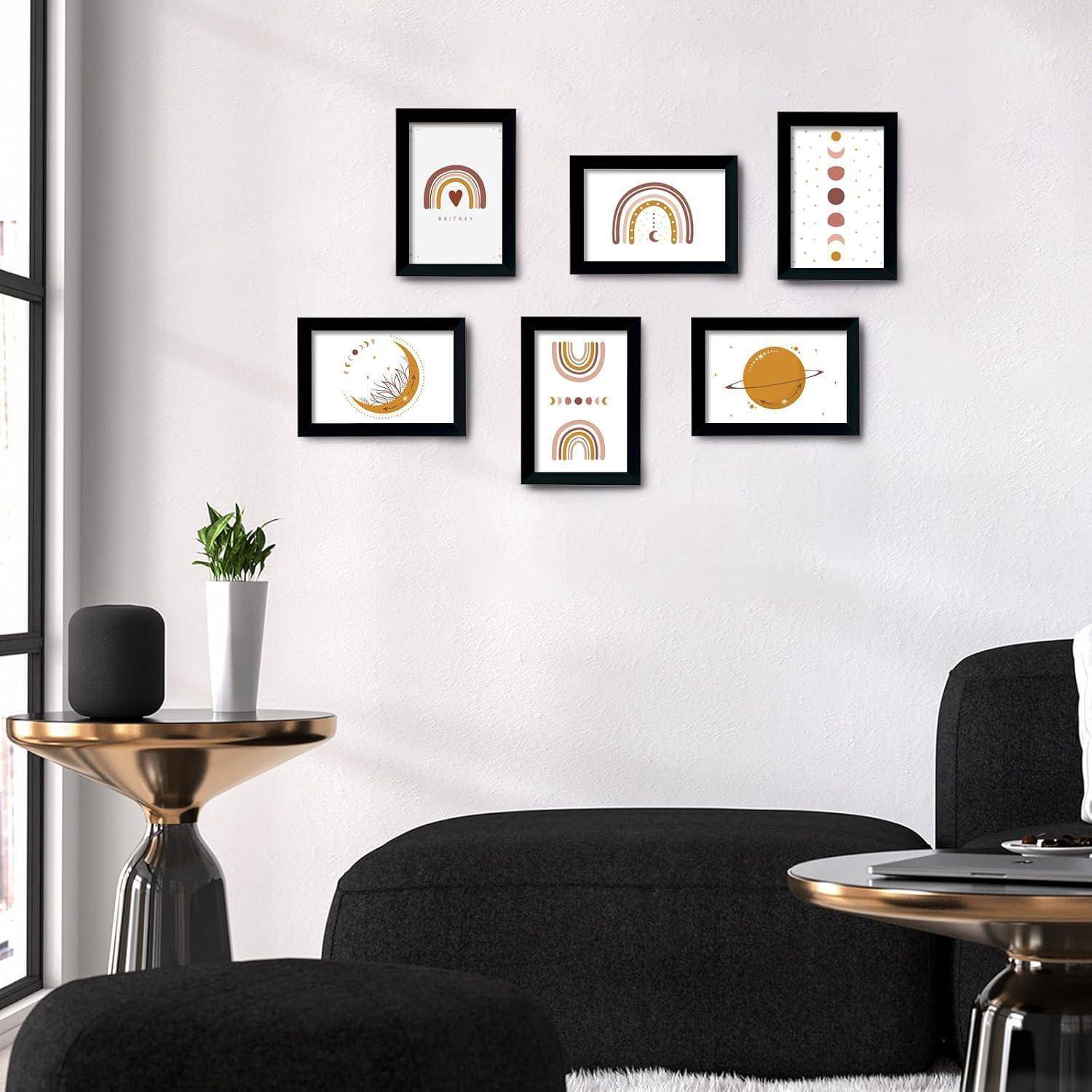 Ein moderner Wohnraum mit einem schwarzen Hocker und einem Beistelltisch. An der Wand befinden sich sechs gerahmte abstrakte Kunstwerke, überwiegend in Orange und Schwarz.