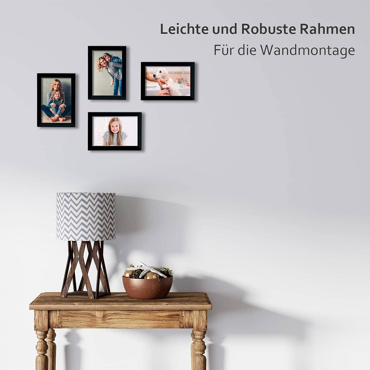 Eine Wand mit vier gerahmten Fotos über einem Holztisch mit einer Lampe und einer Topfpflanze. Text lautet: 'Leichte und robuste Rahmen: Für die Wandmontage'.
