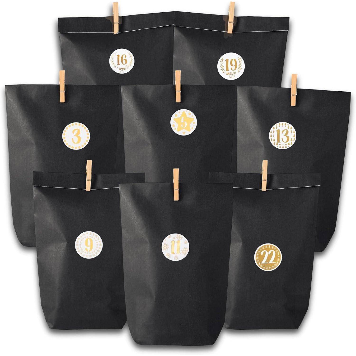 Sieben schwarze Papiertüten mit nummerierten Aufklebern und Holzklammern, in Ebenen angeordnet. Die Nummern sind: 3, 9, 11, 13, 16, 19, 22.