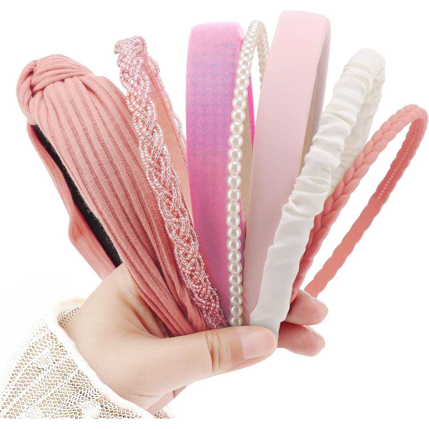 Eine Hand hält sechs verschiedene rosa Haarreife mit unterschiedlichen Texturen wie Spitze, Perlen und geripptem Stoff.