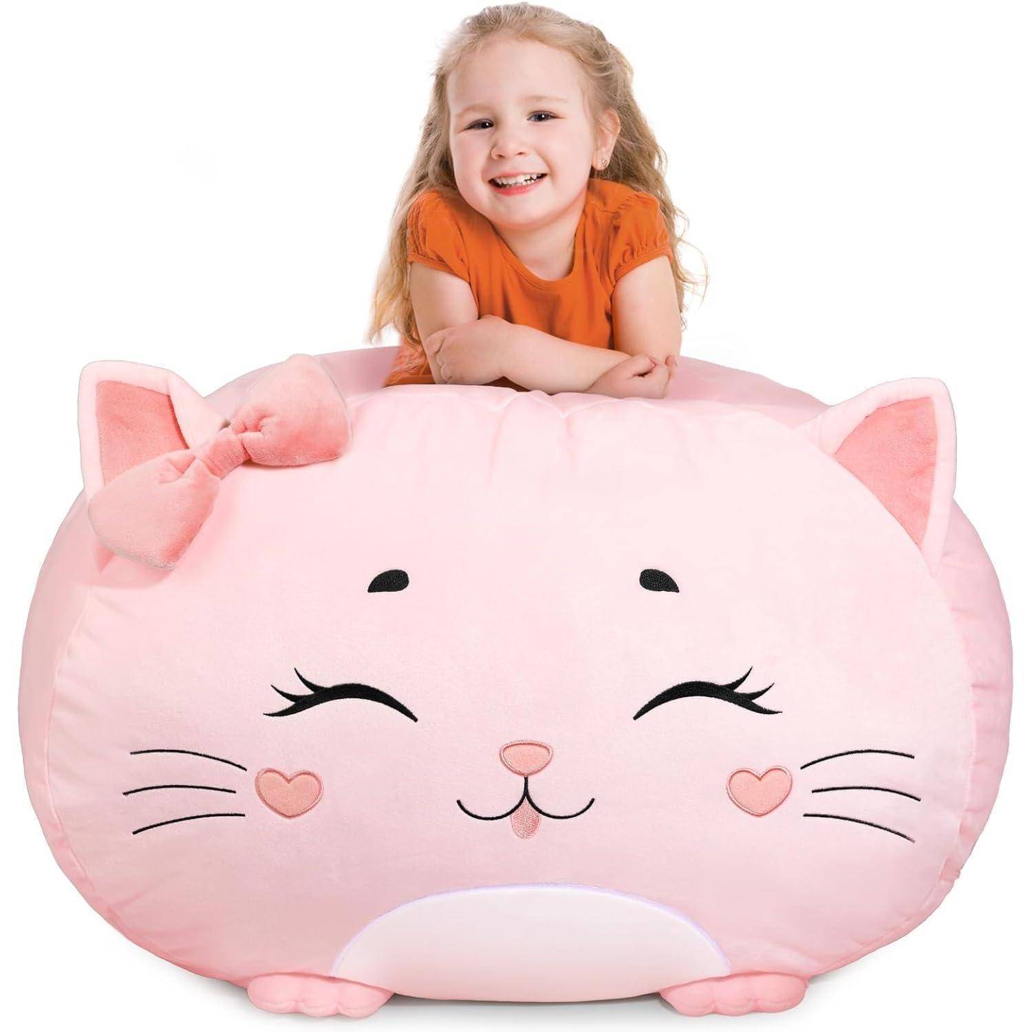 Ein Kind, lächelnd, lehnt sich über einen großen, runden, rosa Katzenplüsch mit einer Schleife am Ohr, mit herzförmigen Wangen und geschlossenen Augen.