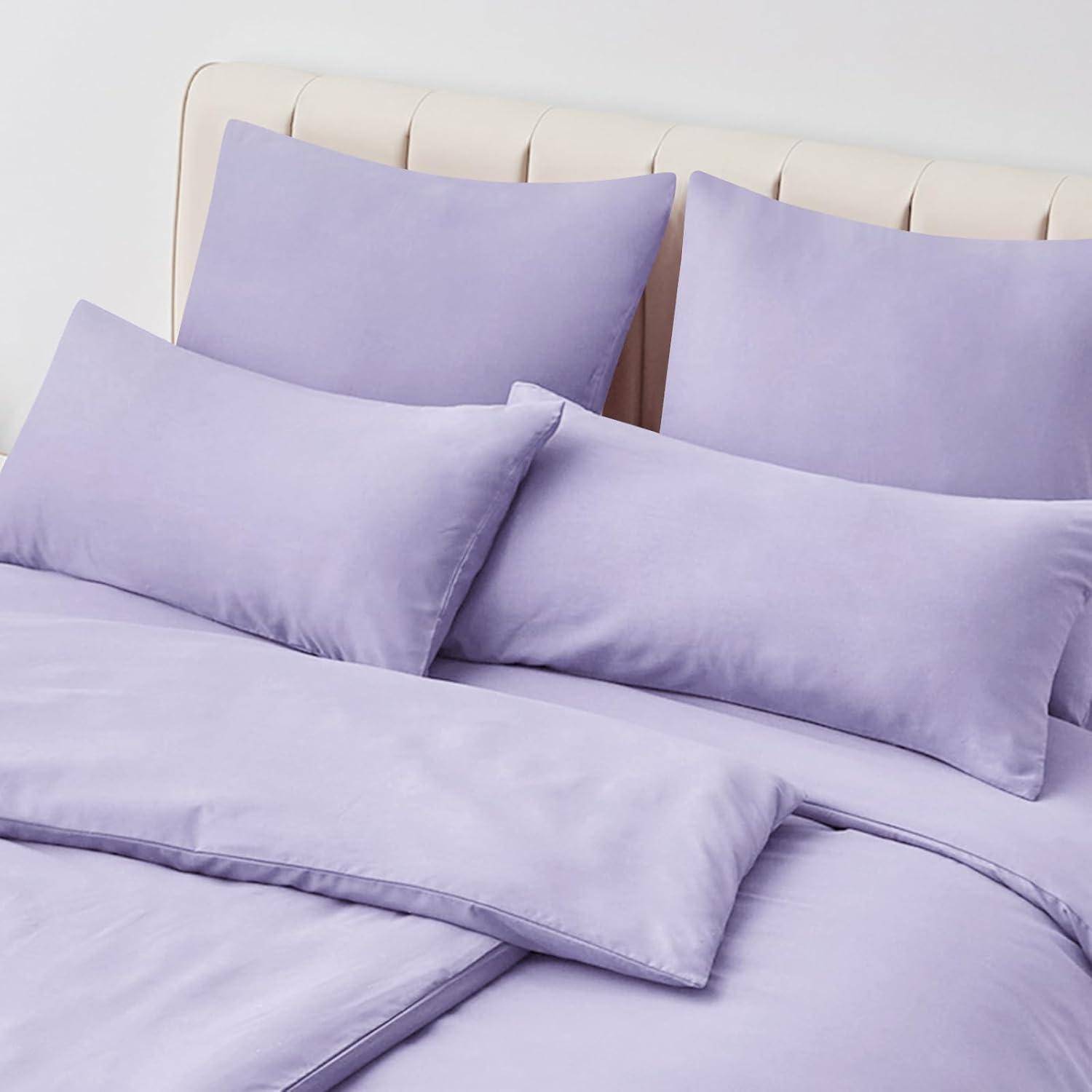 Lila Bettwäsche-Set mit Kissen, Betttüchern und einer Bettdecke auf einem beigen Bett. Die Bettwäsche sieht weich und ordentlich arrangiert aus.