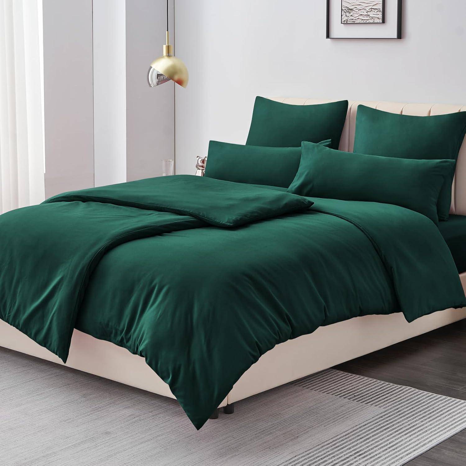 Ein ordentlich gemachtes Bett mit einer grünen Bettdecke und mehreren passenden Kissen in einem hell erleuchteten, modernen Schlafzimmer.