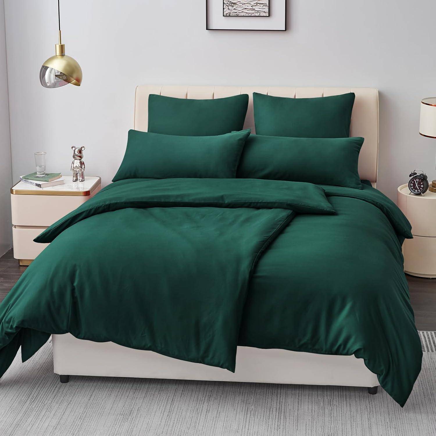 Grünes Bettwäsche-Set auf einem beigen Bett mit passenden Kissen, flankiert von zwei Nachttischen mit Lampen und Dekorationselementen.