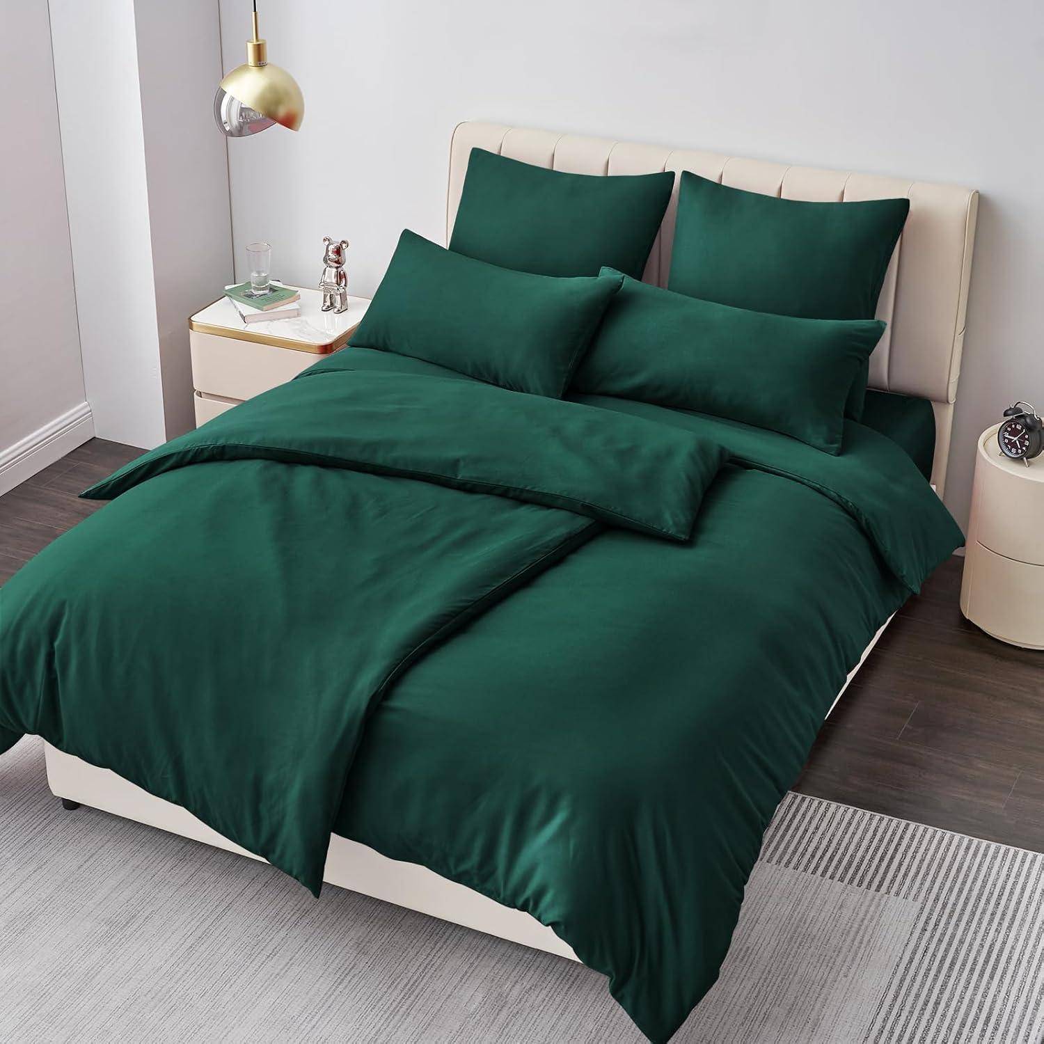 Ein ordentlich gemachtes Bett in einem modernen Schlafzimmer mit dunkelgrüner Bettwäsche, mehreren Kissen, einem Nachttisch mit einer Lampe und einer dekorativen Figur.